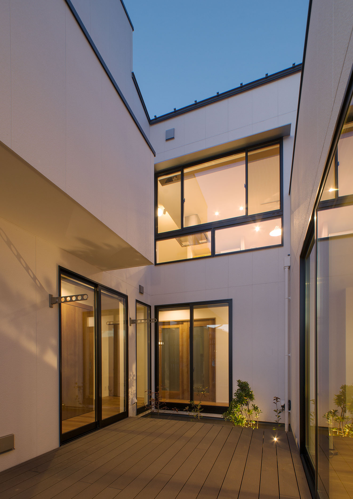 ウッドデッキの中庭に面する窓から光が漏れている様子・デザイン住宅 注文住宅・デザイン住宅建築実例_『CASE677 中庭が繋ぐ家族の気配』_中庭