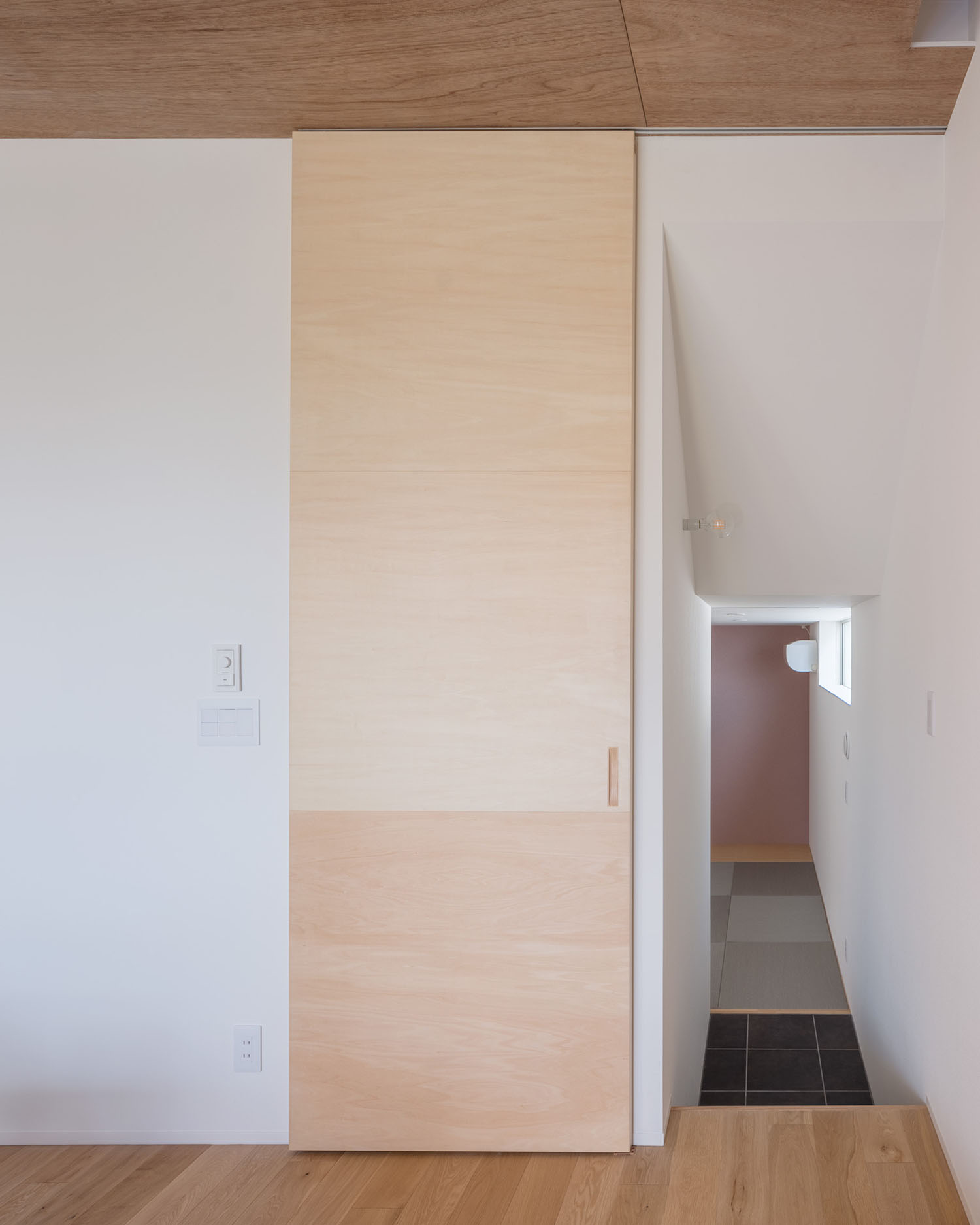 木の扉がついた空間の奥に、黒い琉球畳の和室が見える様子・デザイン住宅 注文住宅・デザイン住宅建築実例_『CASE679 だんだんのいえ』_和室