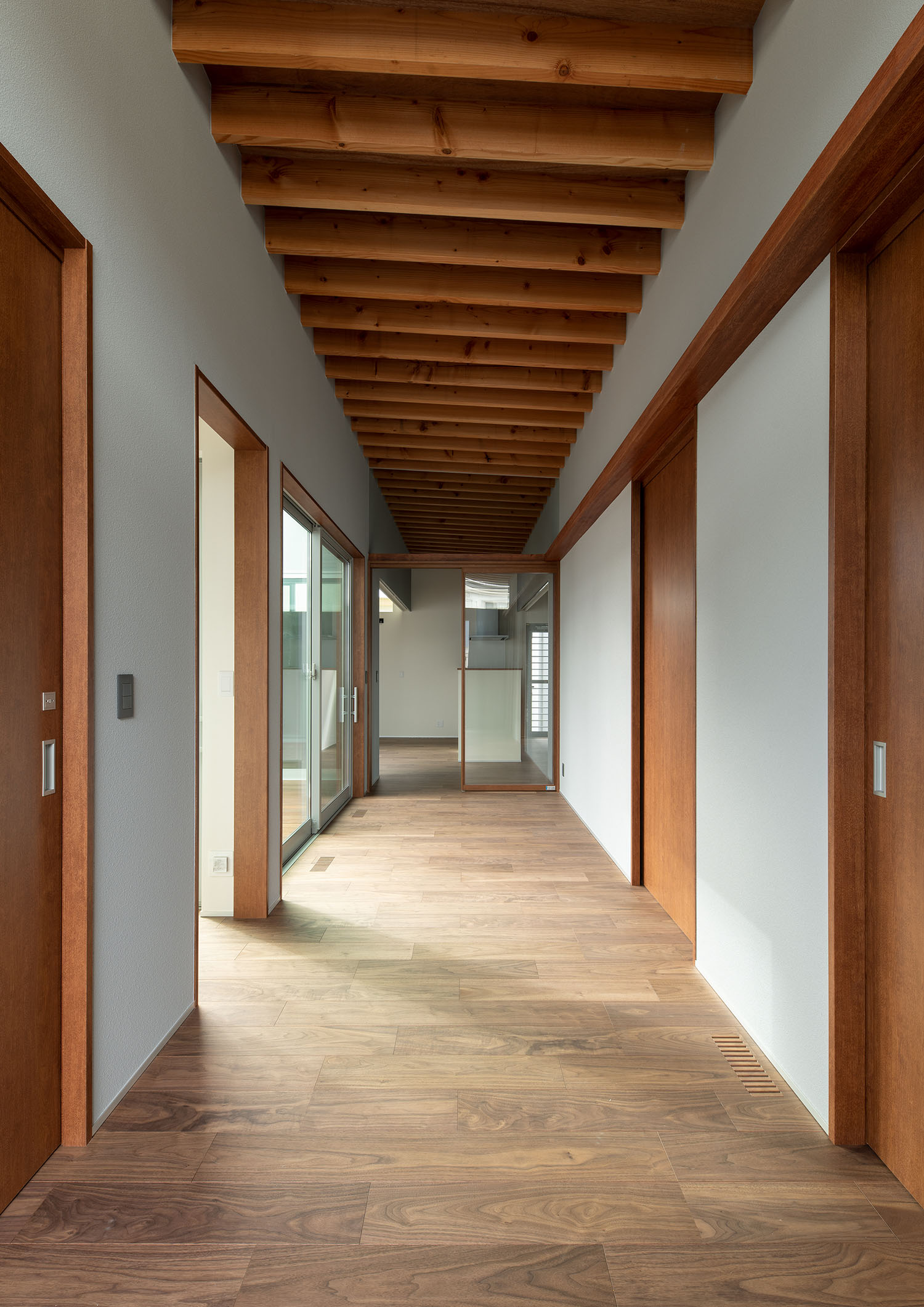 部屋の扉が木で統一された、梁見せ天井の廊下・デザイン住宅 注文住宅・デザイン住宅建築実例_『CASE680 寛か(くつろか)な平屋』_玄関