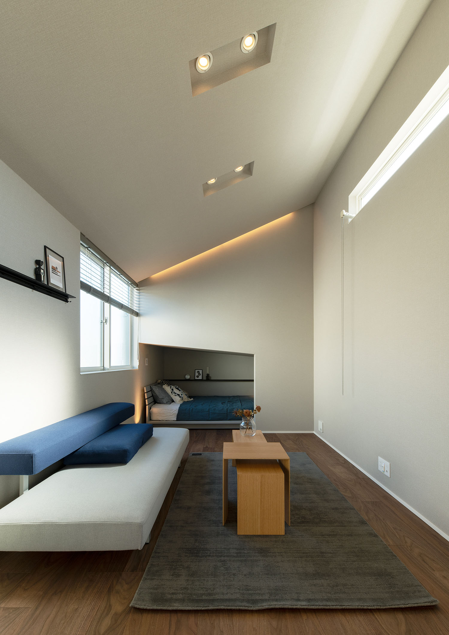 屋根が斜めになっており、壁を切り取るような形でベッドが置かれている部屋・賃貸併用住宅 注文住宅・デザイン住宅建築実例_『CASE681 penche' 「パンシェ」の家』_LDK