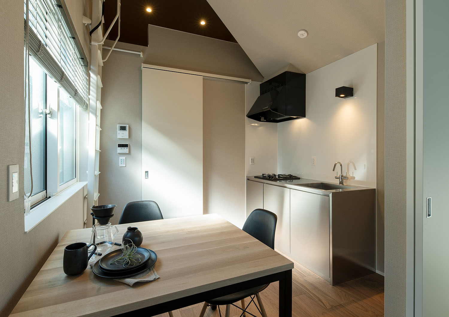 ステンレスの壁付けキッチンがあり、レンジフードやインテリアが黒で統一された部屋・賃貸併用住宅 注文住宅・デザイン住宅建築実例_『CASE681 penche' 「パンシェ」の家』_LDK