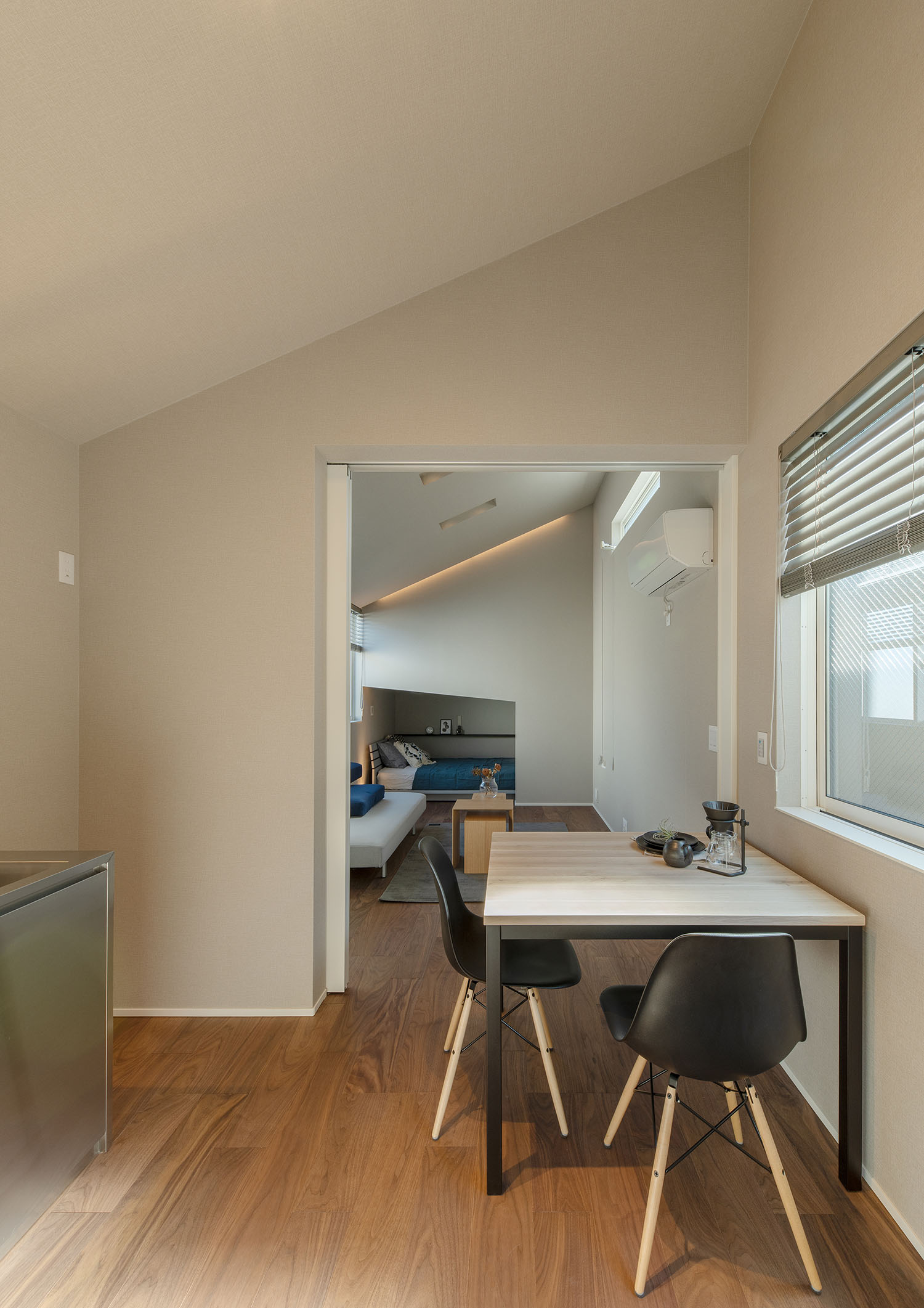 テーブルと黒い椅子があるダイニングからリビングを見た様子・賃貸併用住宅 注文住宅・デザイン住宅建築実例_『CASE681 penche' 「パンシェ」の家』_LDK