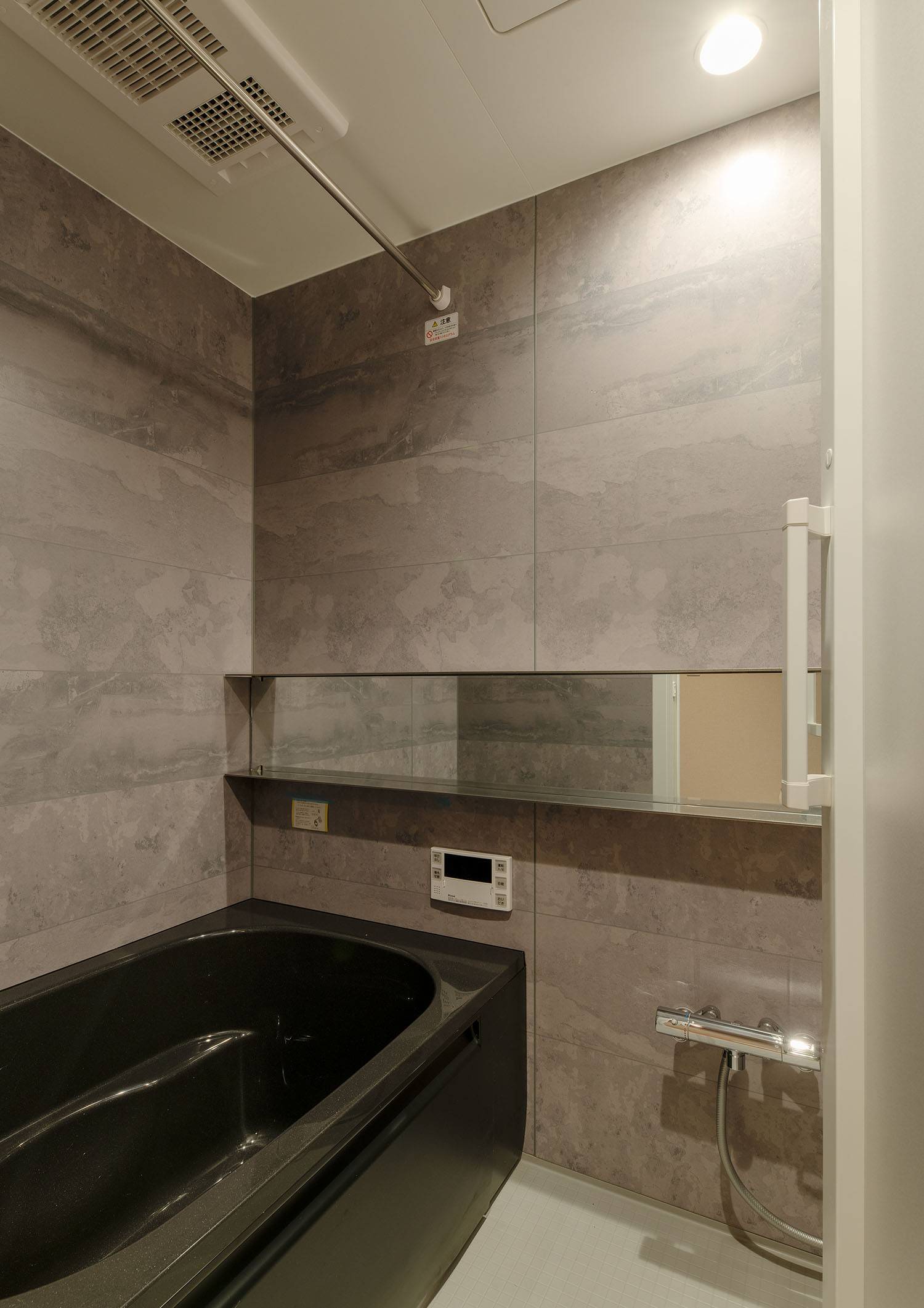 石のような壁で、黒いバスタブがある浴室・賃貸併用住宅 注文住宅・デザイン住宅建築実例_『CASE681 penche' 「パンシェ」の家』_浴室・洗面所