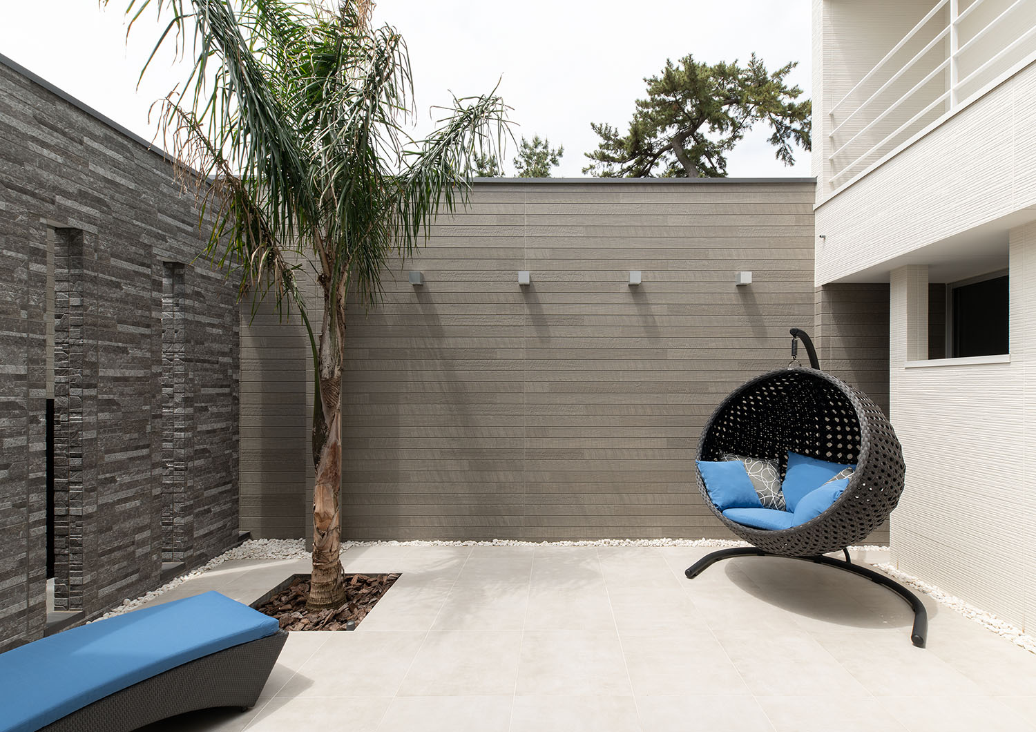グレーの壁で囲まれておりヤシの木やハンモックチェアがある中庭・デザイン住宅 注文住宅・デザイン住宅建築実例_『CASE682 Casa de Resort』_中庭