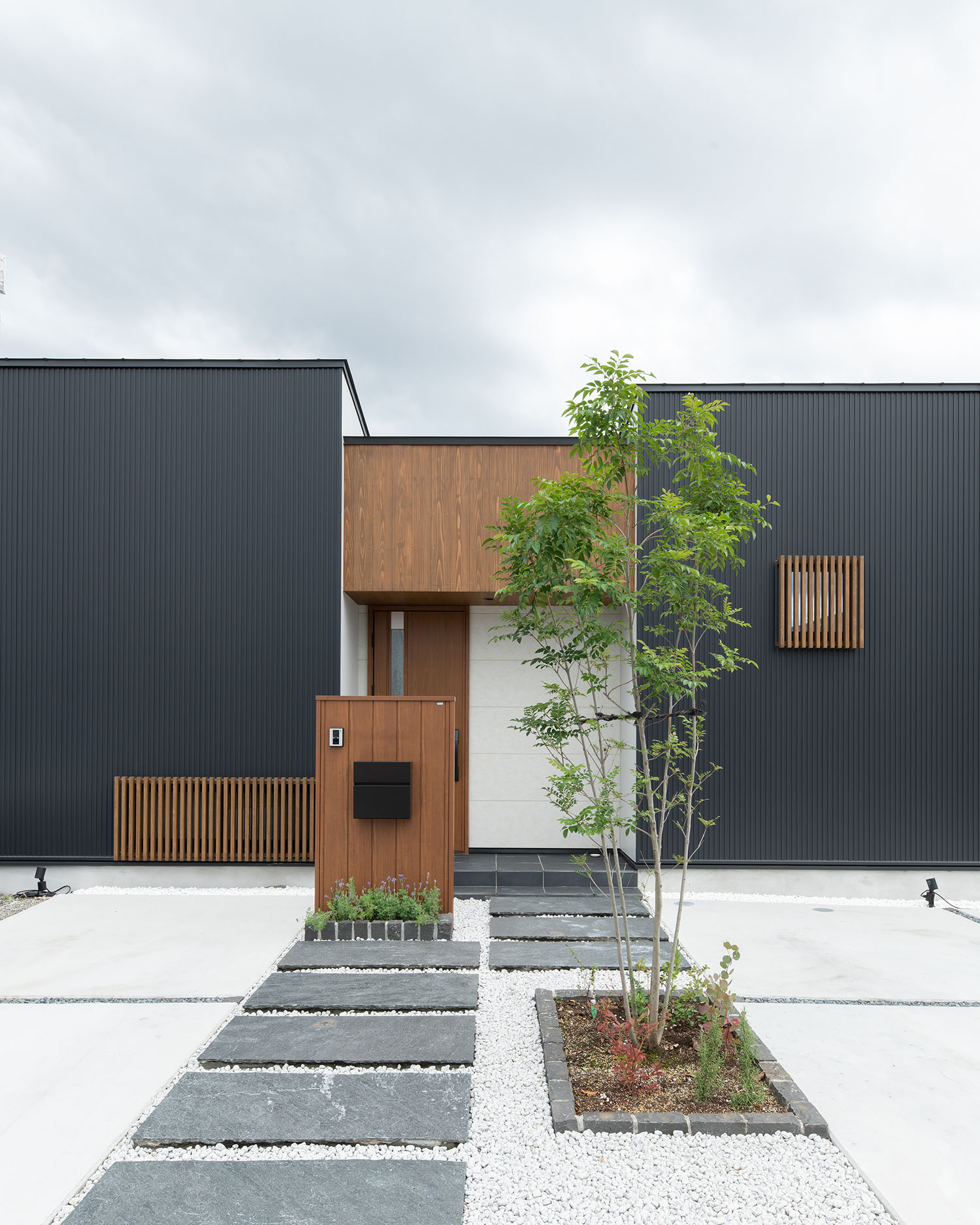 正面にシンボルツリーがある、黒い外壁に木材がアクセントとなった住宅の外観・デザイン住宅 注文住宅・デザイン住宅建築実例_『CASE683 丘の上のハウス』_外観