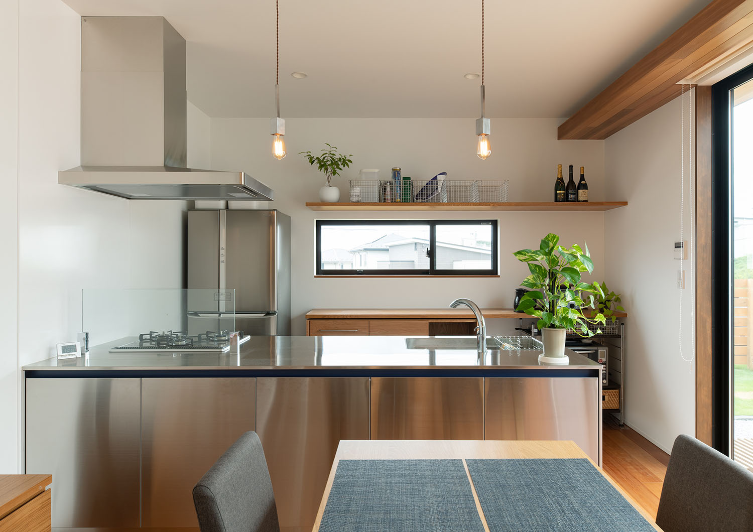 天井からペンダントライトが吊り下げられているステンレスのペニンシュラキッチン・デザイン住宅 注文住宅・デザイン住宅建築実例_『CASE683 丘の上のハウス』_キッチン