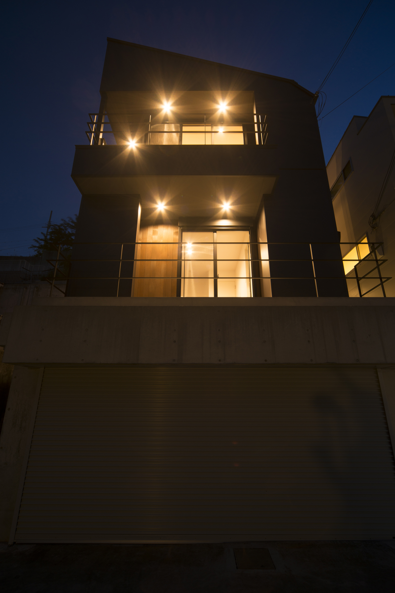 高台にあるバルコニーとテラス付きの家を下から見た様子・デザイン住宅