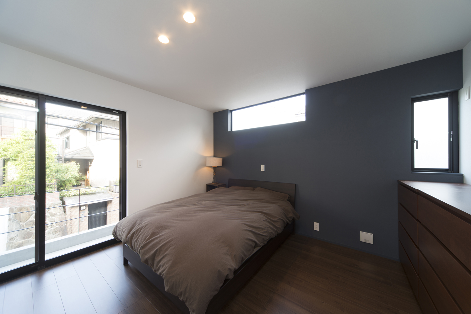 黒アクセントクロスがありバルコニーに面した落ち着きのある寝室・デザイン住宅