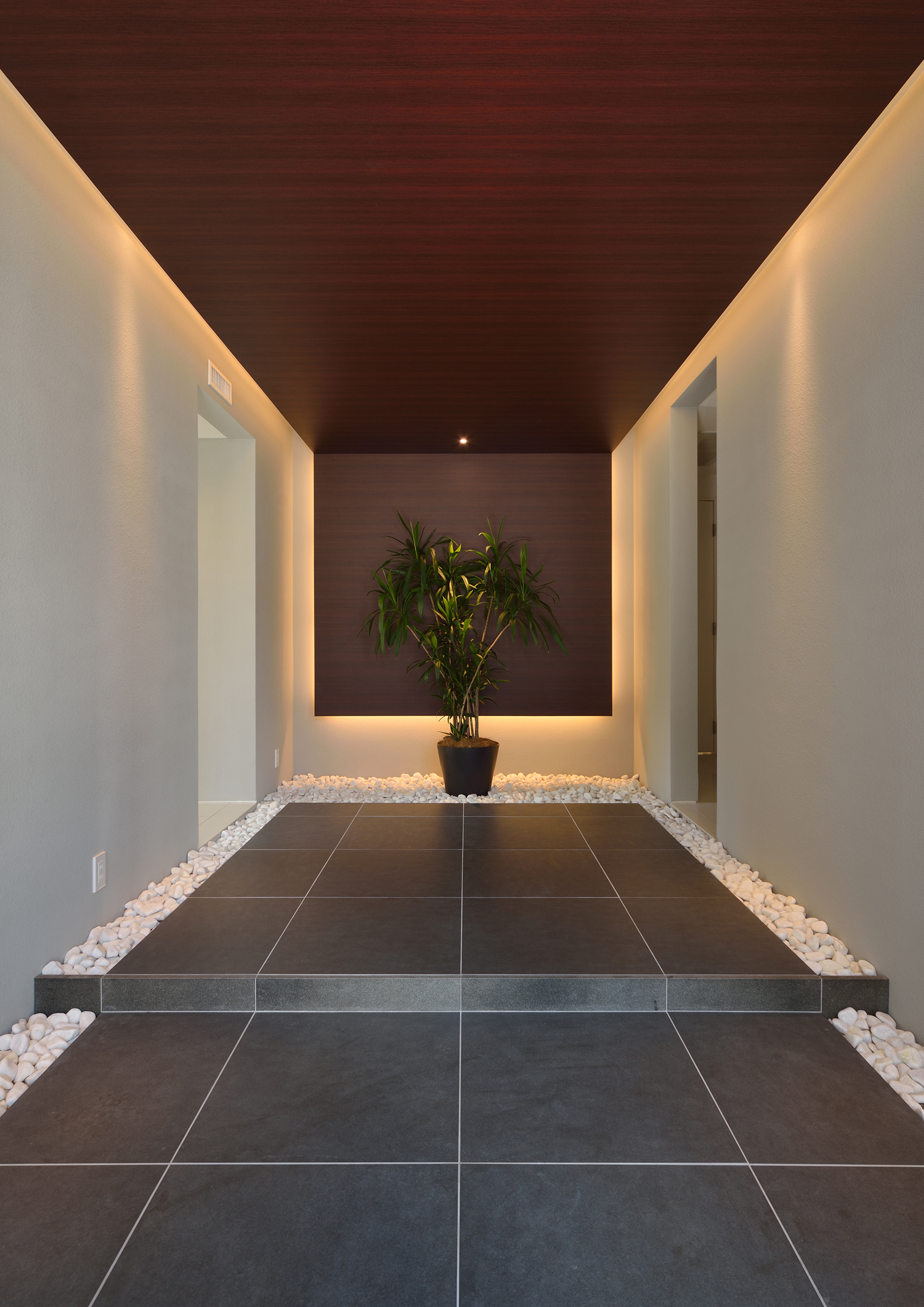 グレーのタイルと間接照明付きの木の天井がある高級感のある玄関・デザイン住宅