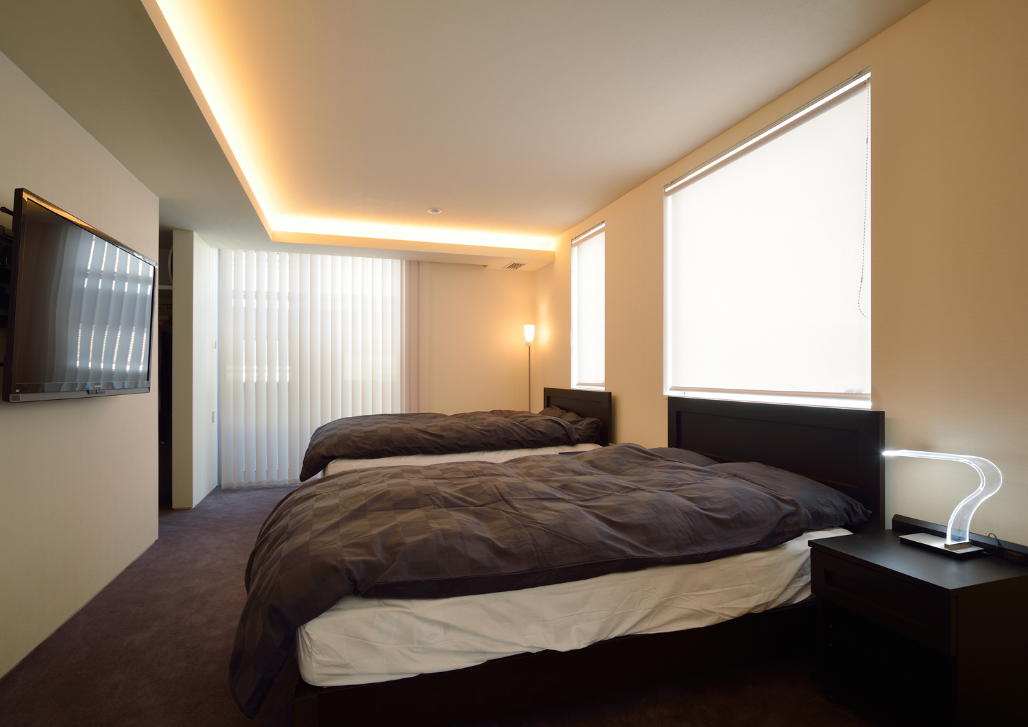 壁際に間接照明を取り付けたベッドが二台並ぶホテルライクな寝室・デザイン住宅