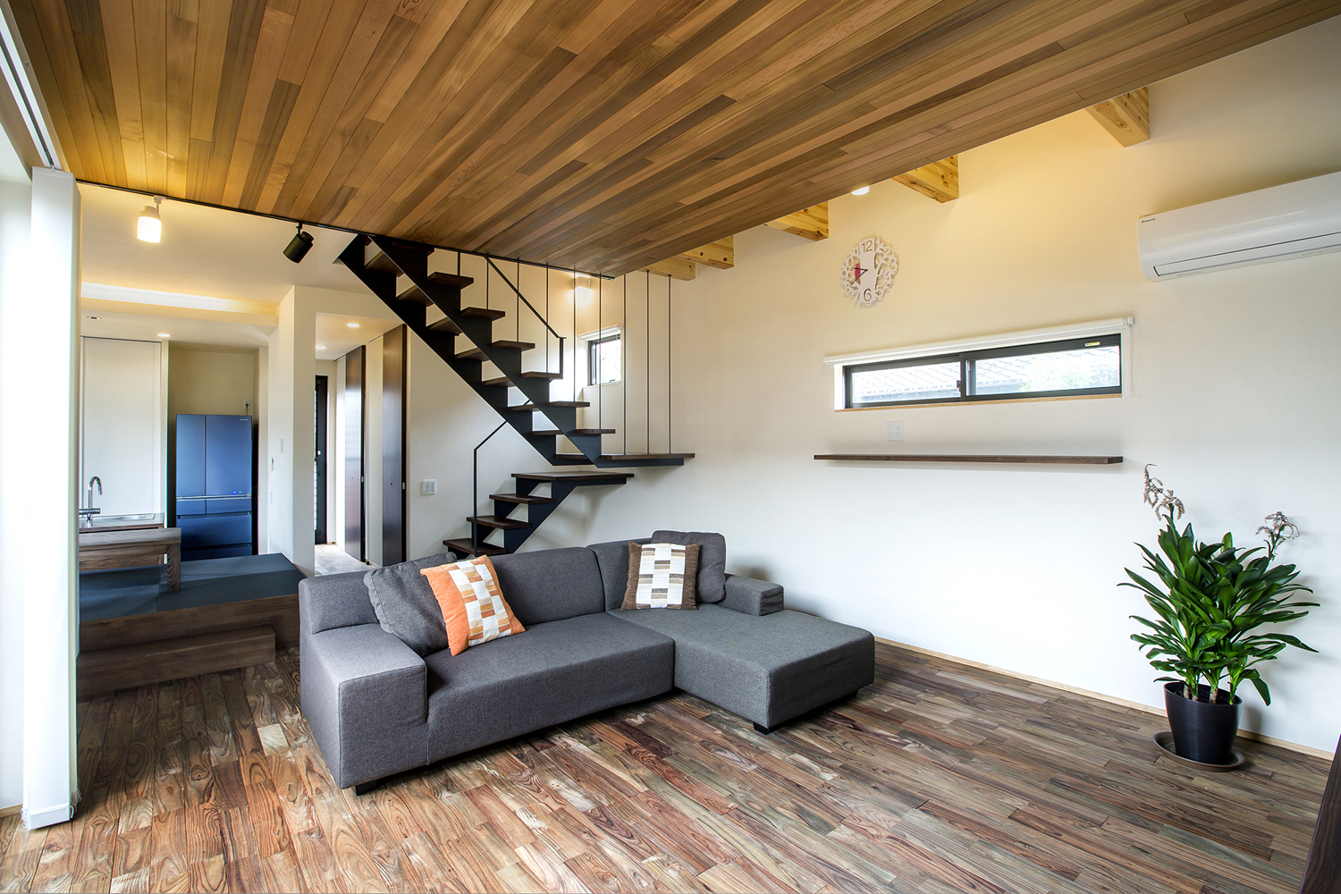 ワイヤーで吊るされたスケルトンのリビングイン階段がある木目の天井でフローリングのLDK・デザイン住宅