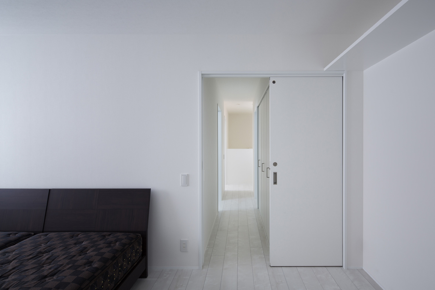 引き戸が取り付けられた白い壁のシンプルな寝室・デザイン住宅
