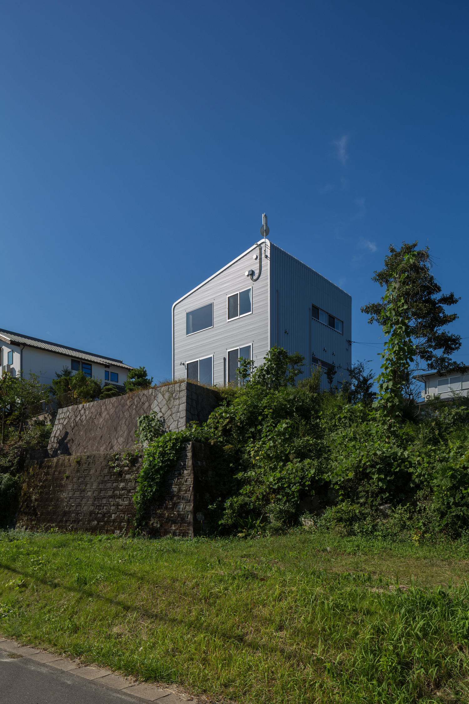 緑に囲まれた丘の上に建つシンプルなシルバーの外壁の家・デザイン住宅