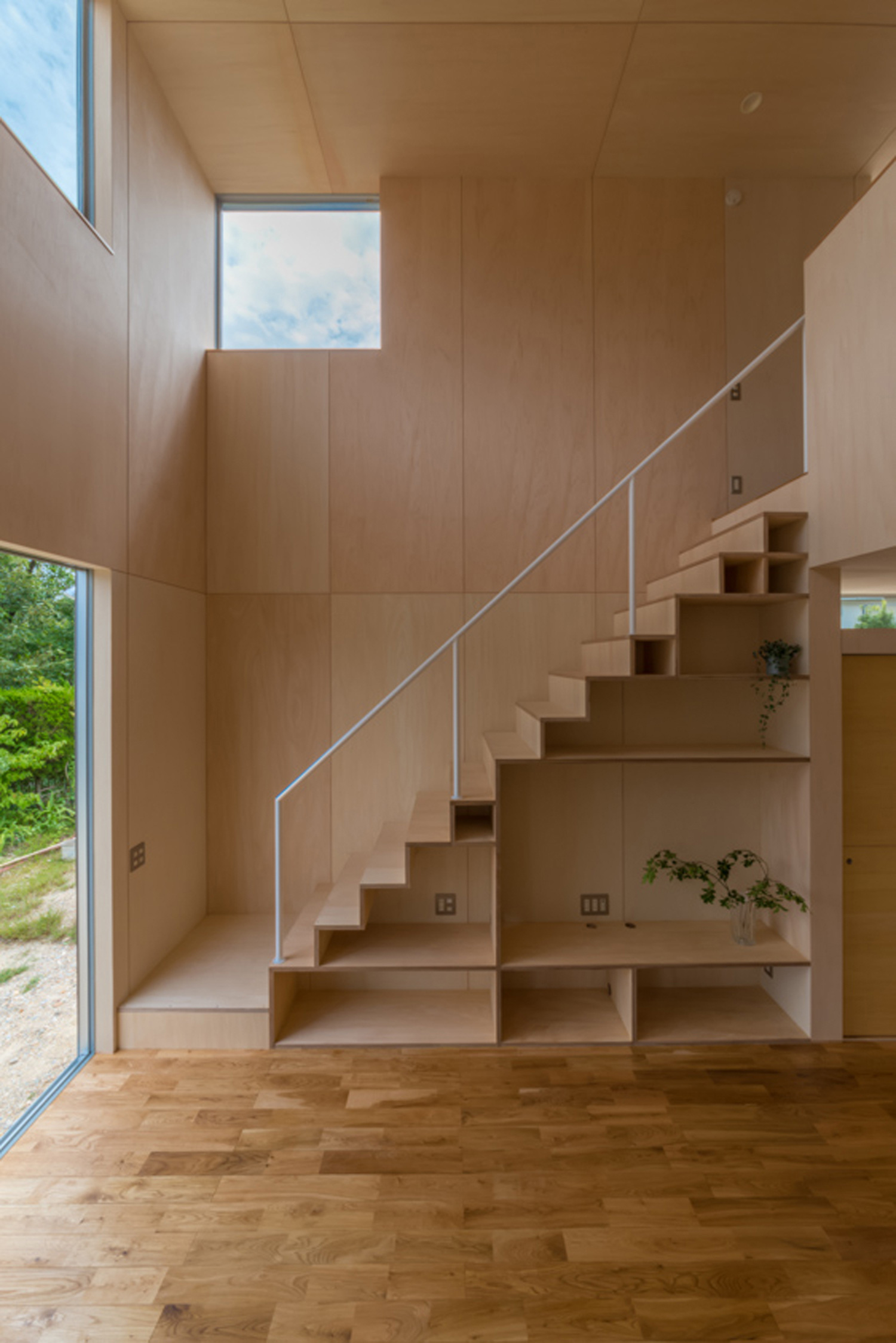 壁と天井が木目で、スケルトン階段下に壁面収納を取り付けた吹き抜けのLDK・デザイン住宅