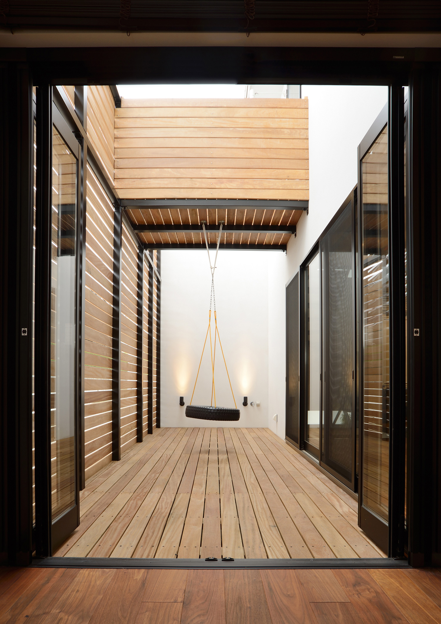 木のルーバーの目隠し壁に囲まれたウッドデッキのナチュラルなテラス・デザイン住宅