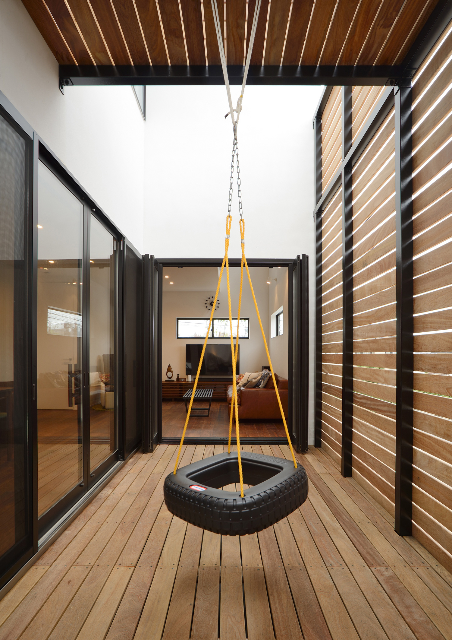 タイヤのブランコがある木のルーバーの目隠し付きのテラス・デザイン住宅