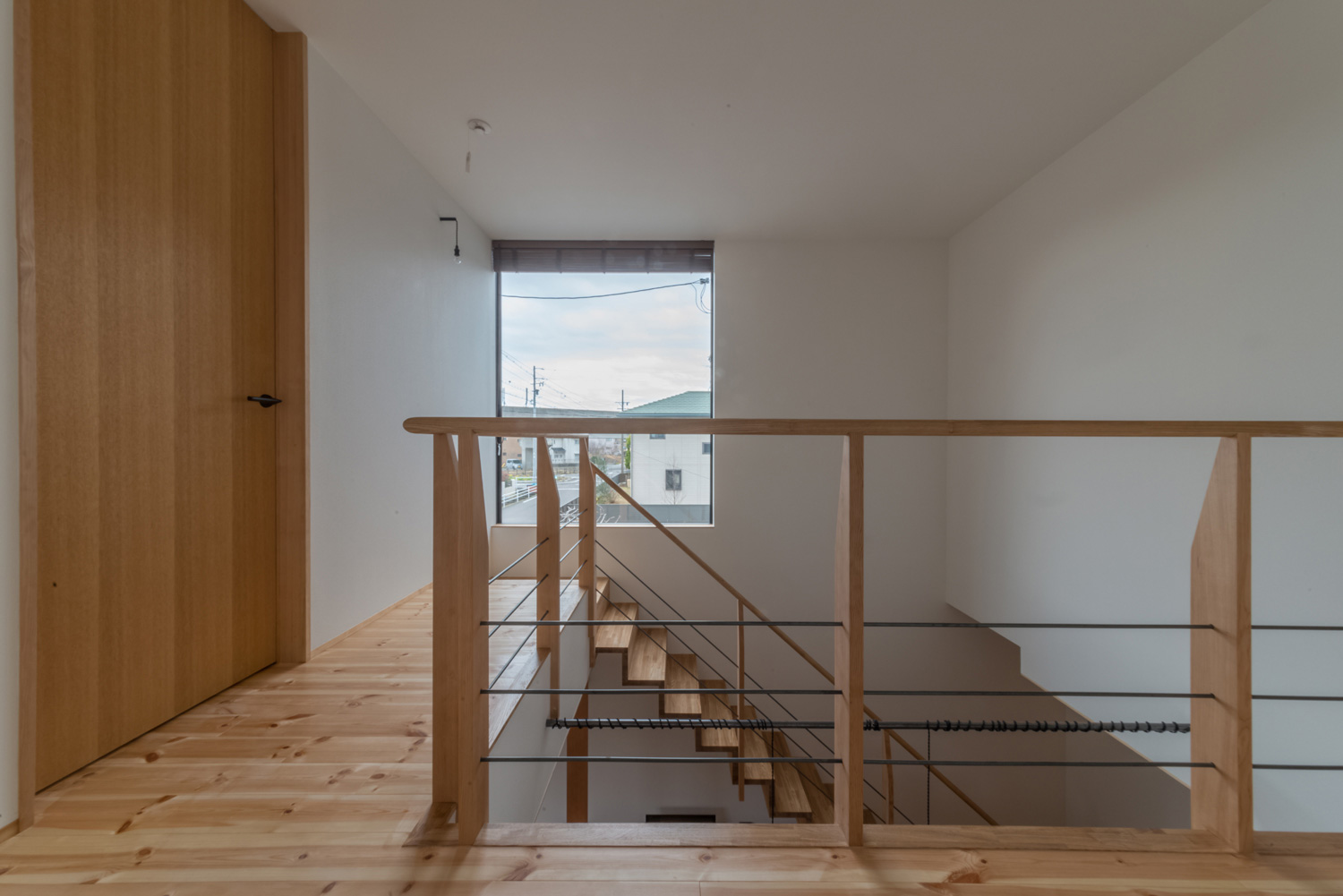 突き当りに大きな窓がある吹き抜けに面した二階の廊下・デザイン住宅