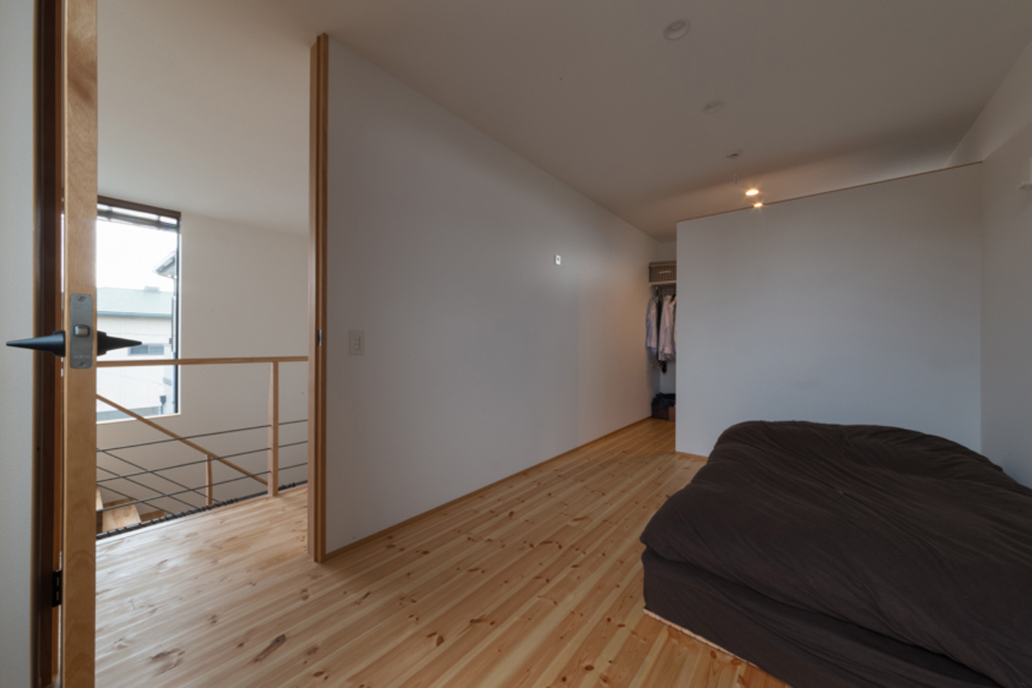 ウォークインクローゼットと壁で仕切られたシンプルな寝室・デザイン住宅