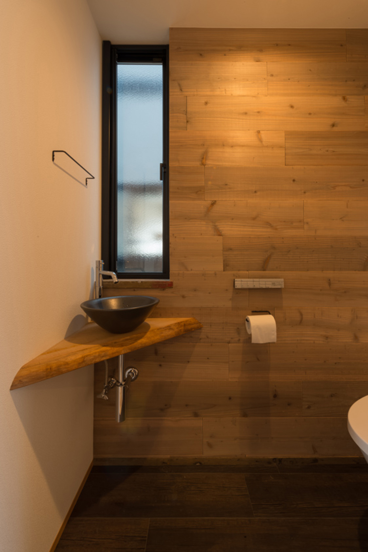 木目の壁で、コンパクトな手洗いカウンターがあるおしゃれなトイレ・デザイン住宅