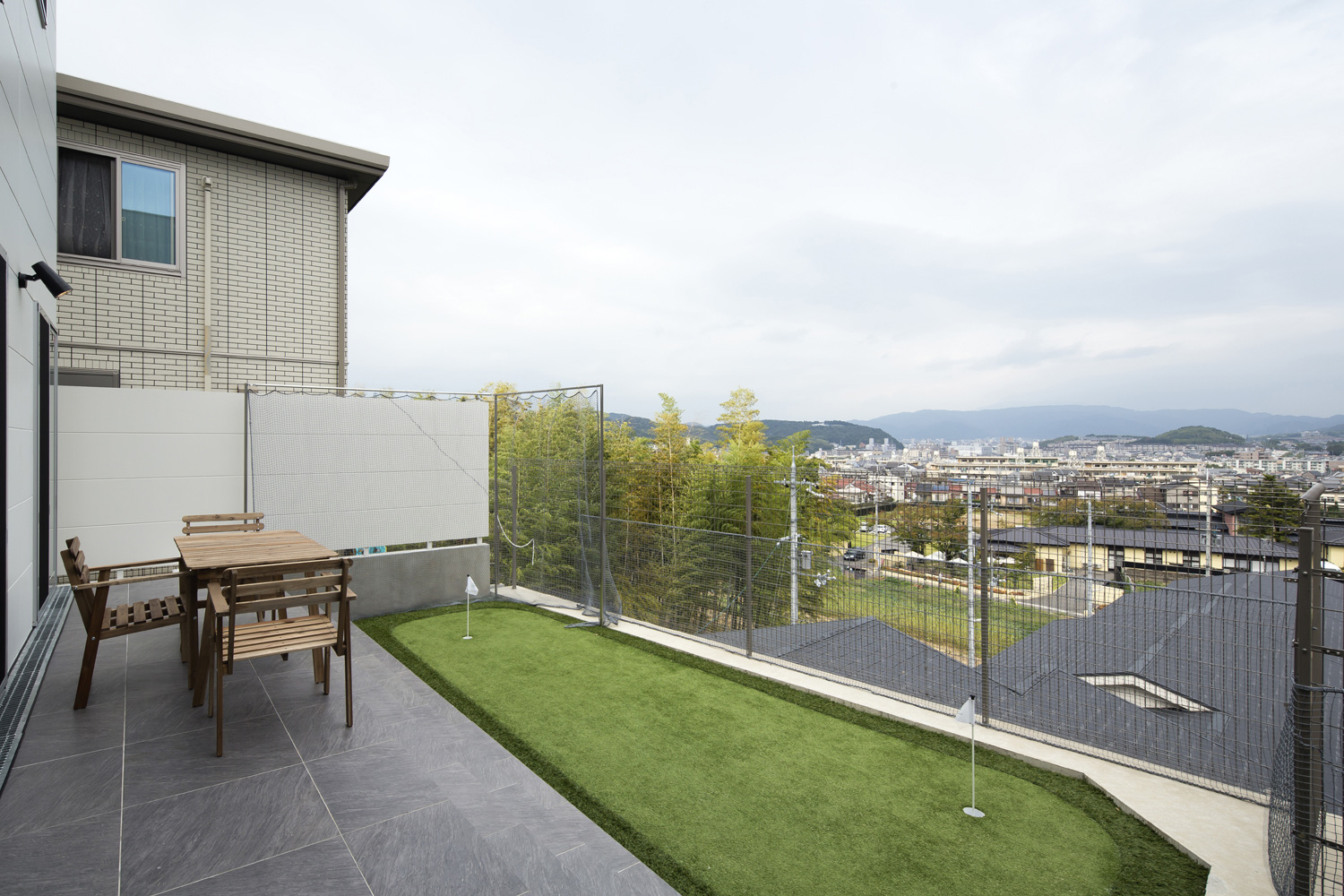 椅子とテーブルを置いた芝生がある見晴らしの良いバルコニー・デザイン住宅