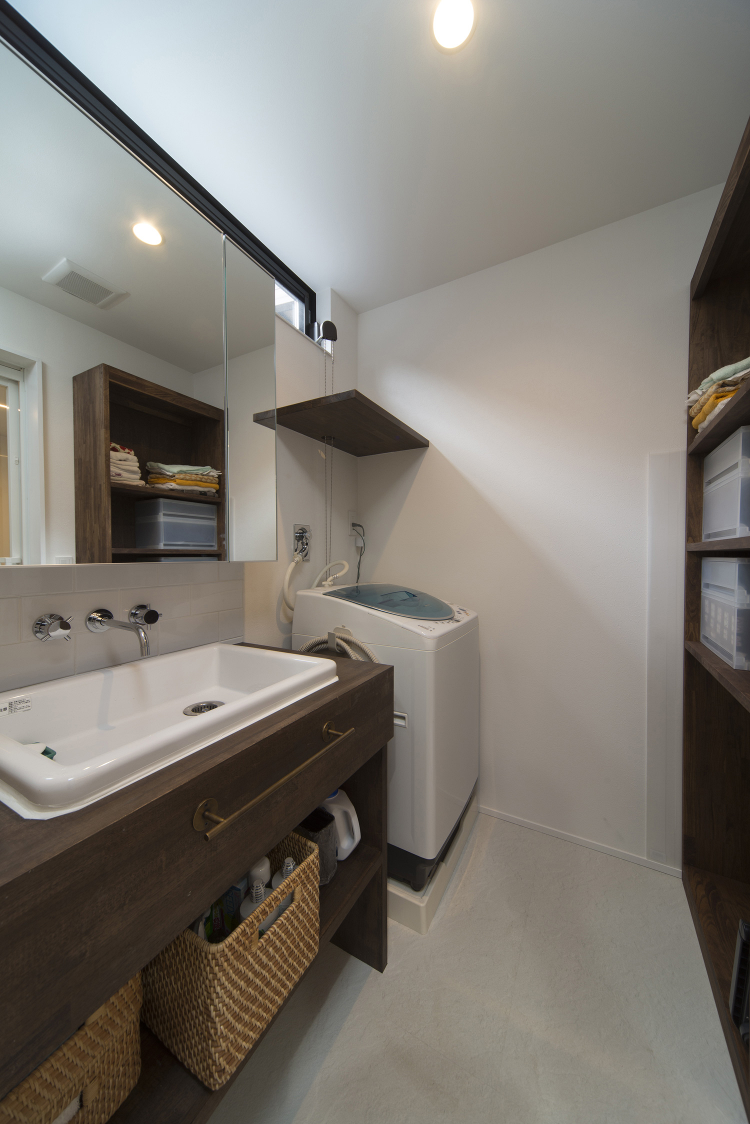 濃い色の木材を洗面台や収納棚に使った洗面所・デザイン住宅