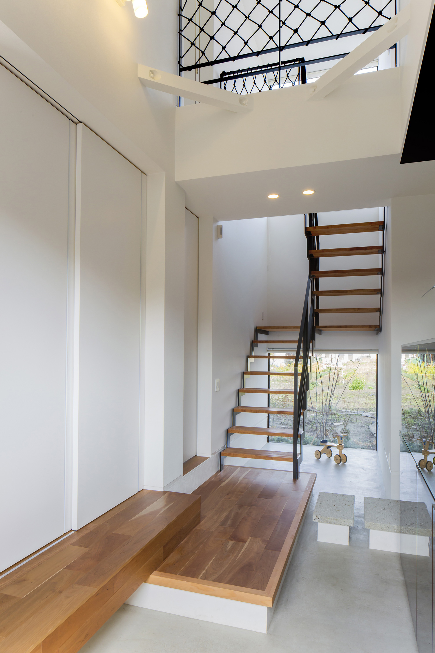 吹き抜けのある開放的なモルタルの玄関・デザイン住宅