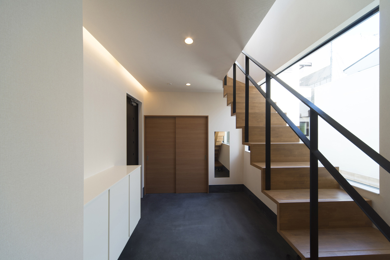 黒いアイアンの手すりが取り付けられたスケルトン階段がある廊下・デザイン住宅