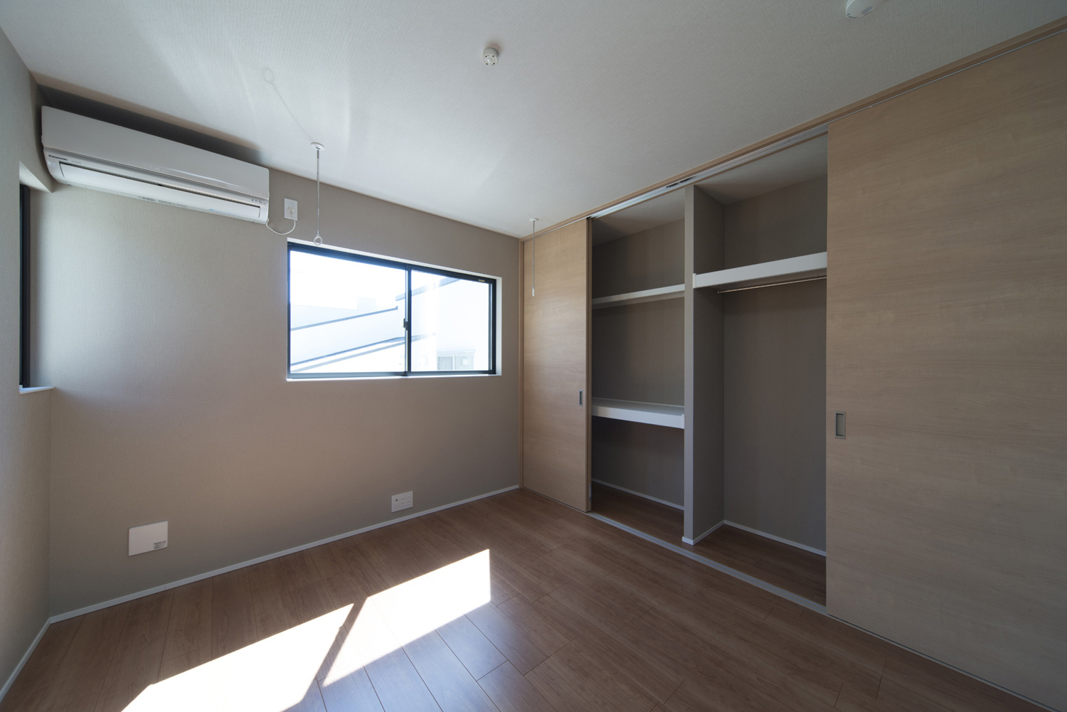 木目の扉付きのクローゼットがあるシンプルな寝室・デザイン住宅