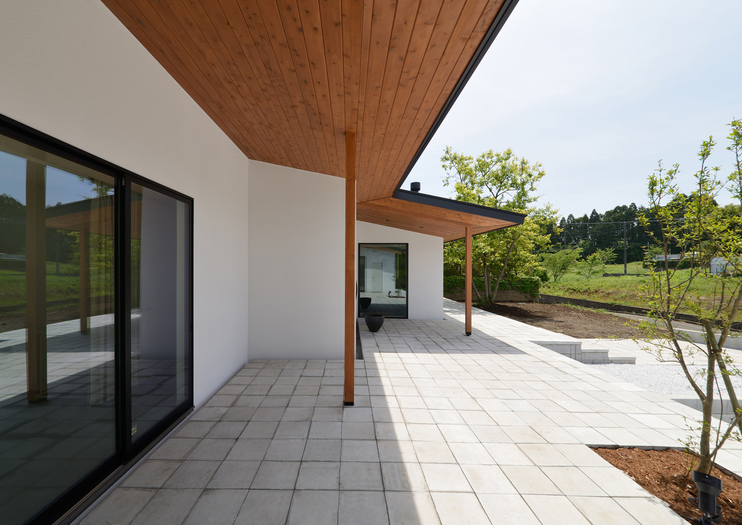 木目の深い軒天井があるタイルのテラス・デザイン住宅