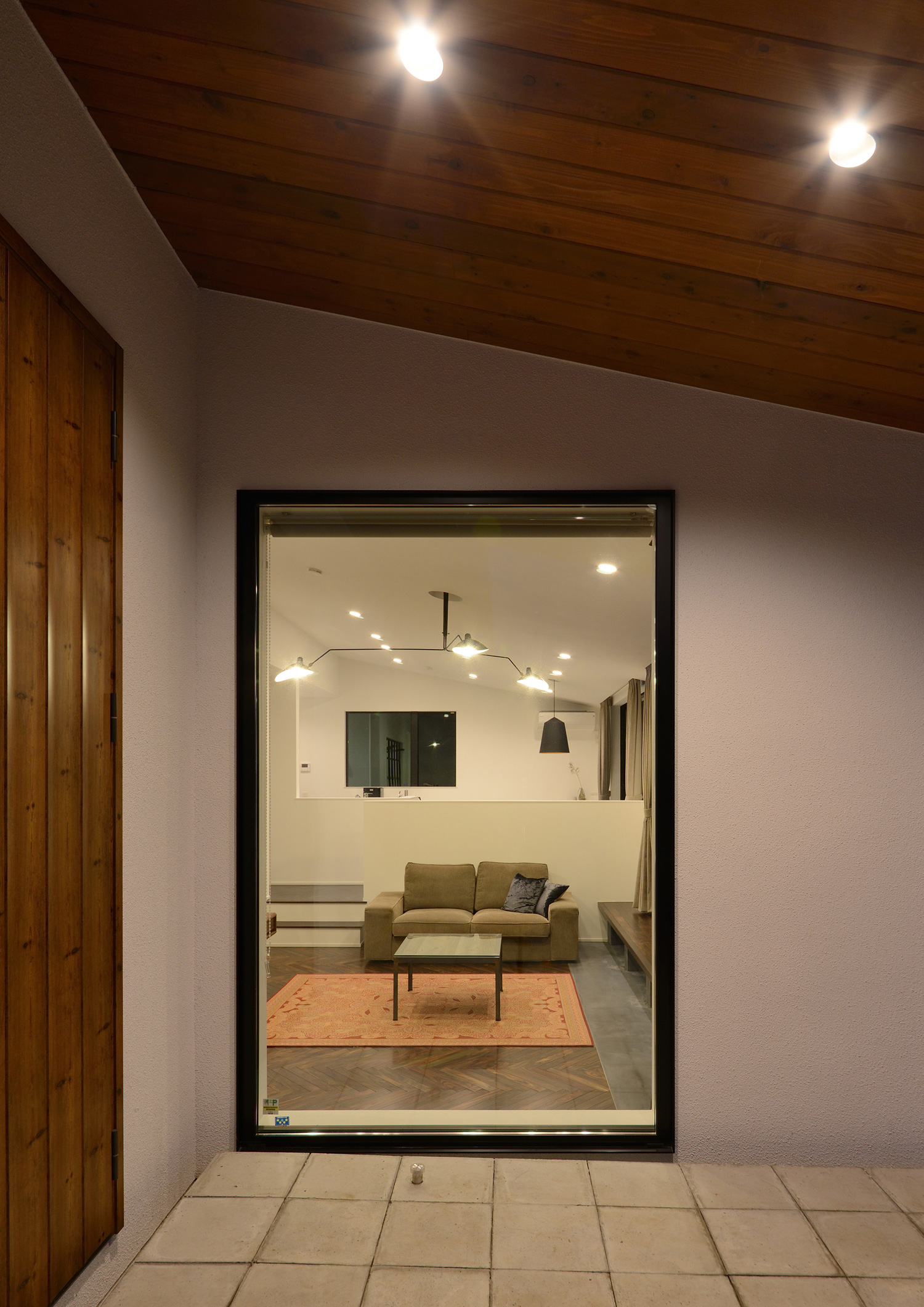 ダウンライト付きの軒天井と室内が見える窓がある玄関ポーチ・デザイン住宅