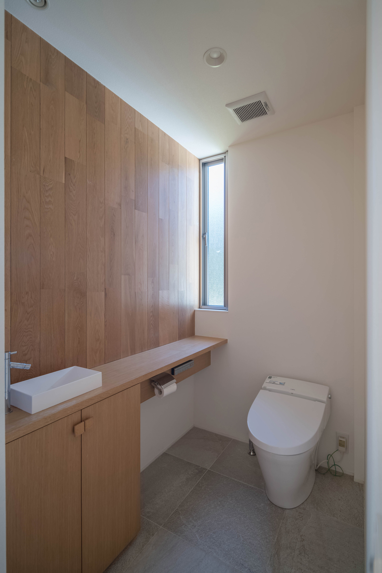 スリット窓を取り付けた木のアクセントクロスや薄型手洗いがあるトイレ・デザイン住宅 注文住宅・デザイン住宅建築実例_『CASE495 舞台の家』_トイレ