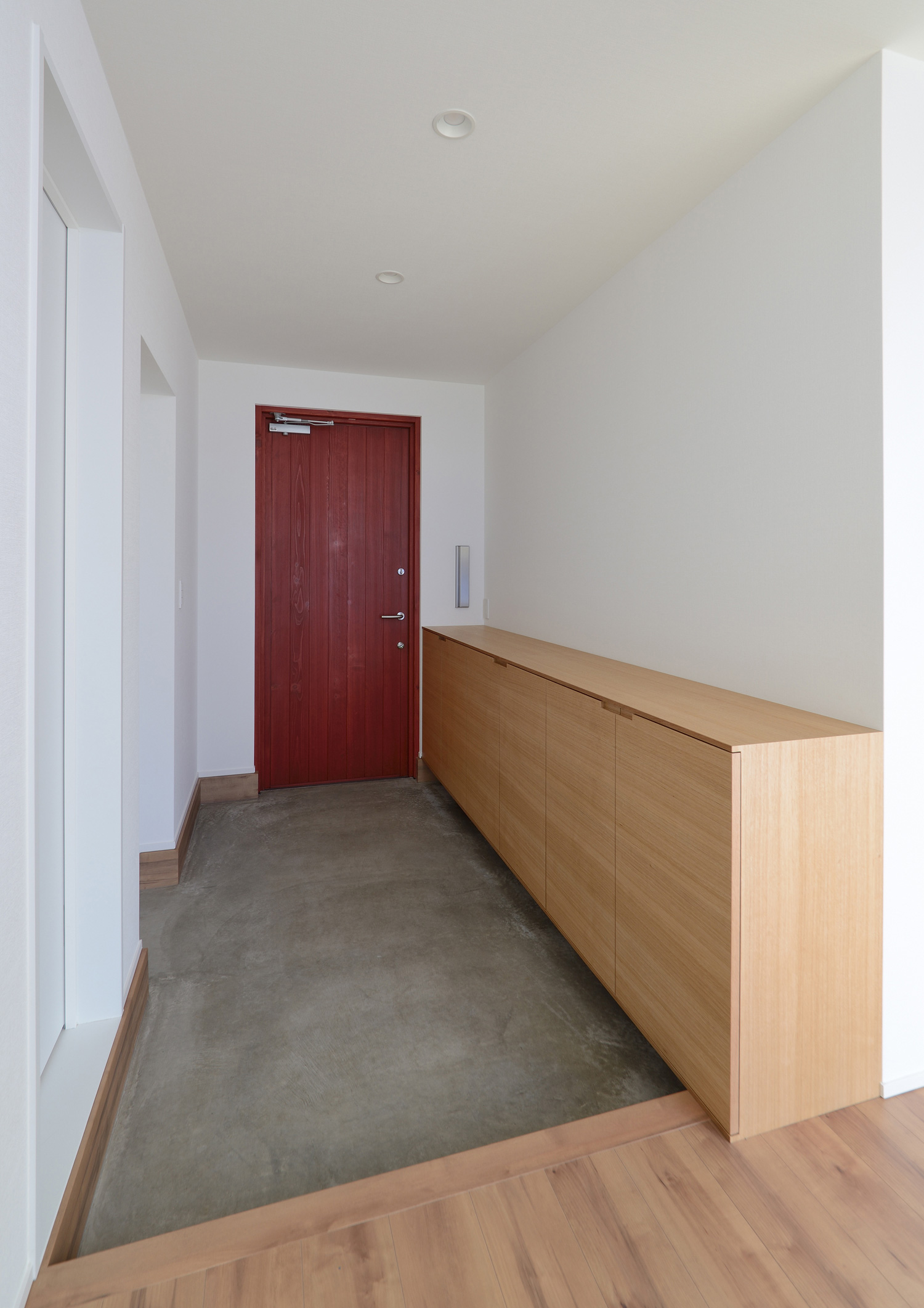 赤い玄関扉や、木のシューズボックスがあるモルタルの玄関・デザイン住宅 注文住宅・デザイン住宅建築実例_『CASE498 シロイイエ』_玄関