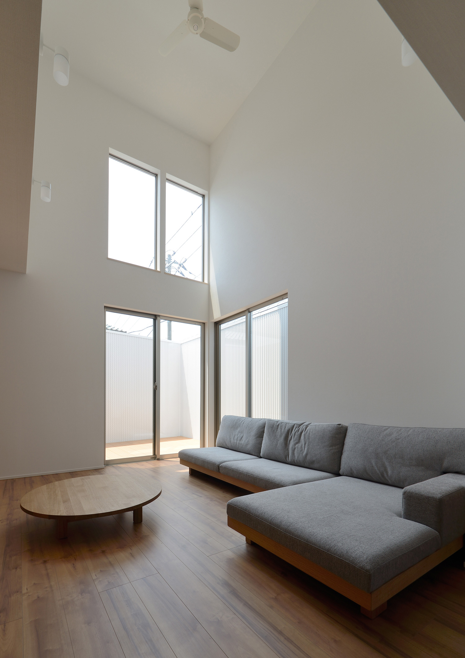 グレーのL字ソファを置いた吹き抜けのある開放的なLDK・デザイン住宅 注文住宅・デザイン住宅建築実例_『CASE498 シロイイエ』_LDK