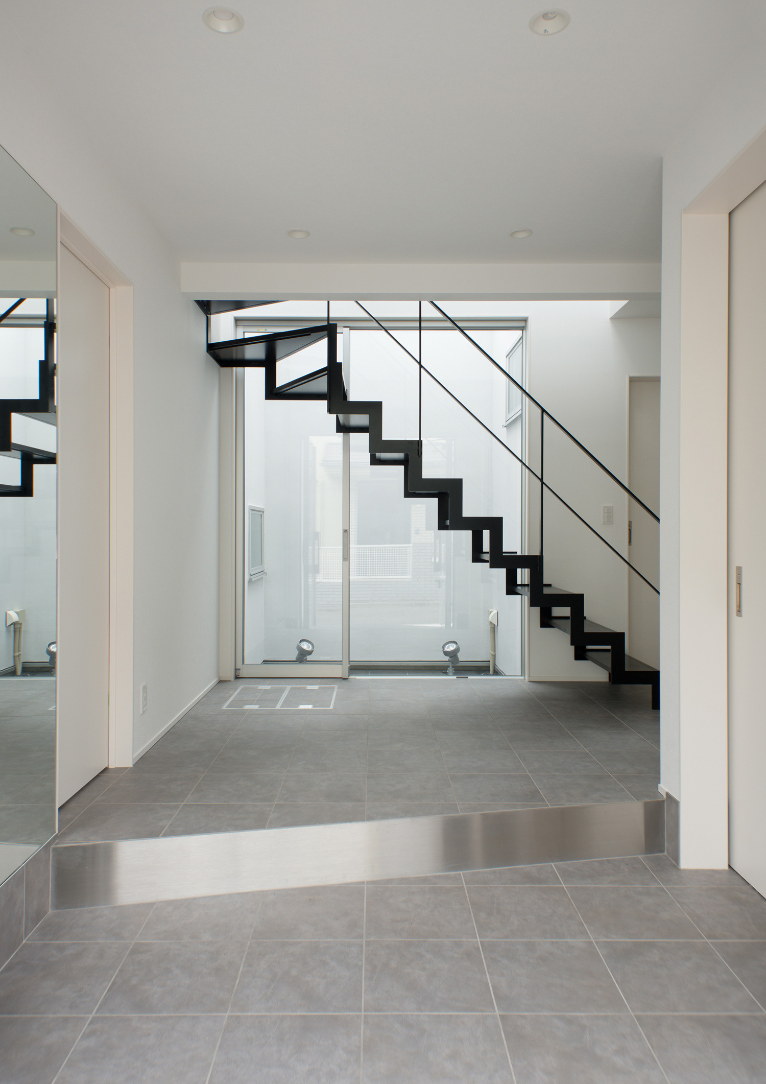 正面にスケルトン階段と窓があるグレーのタイルの玄関・デザイン住宅 注文住宅・デザイン住宅建築実例_『CASE522 LAYER – HOUSE』_玄関