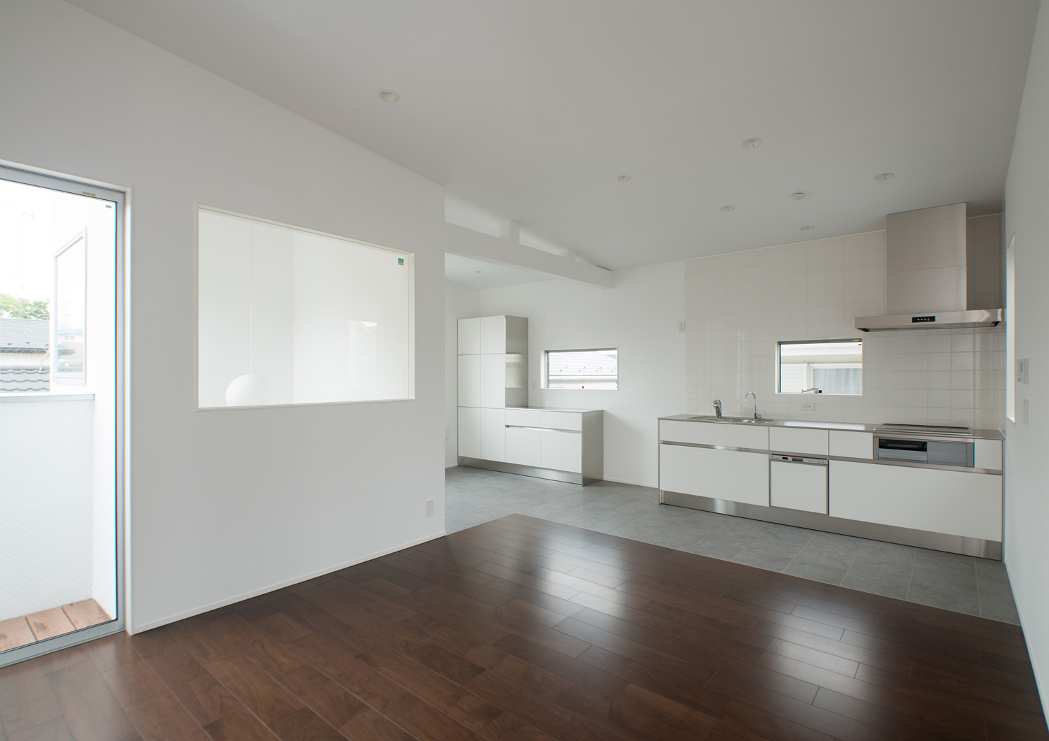 壁付けのキッチンがあるウォルナットのフローリングのLDK・デザイン住宅 注文住宅・デザイン住宅建築実例_『CASE522 LAYER – HOUSE』_LDK