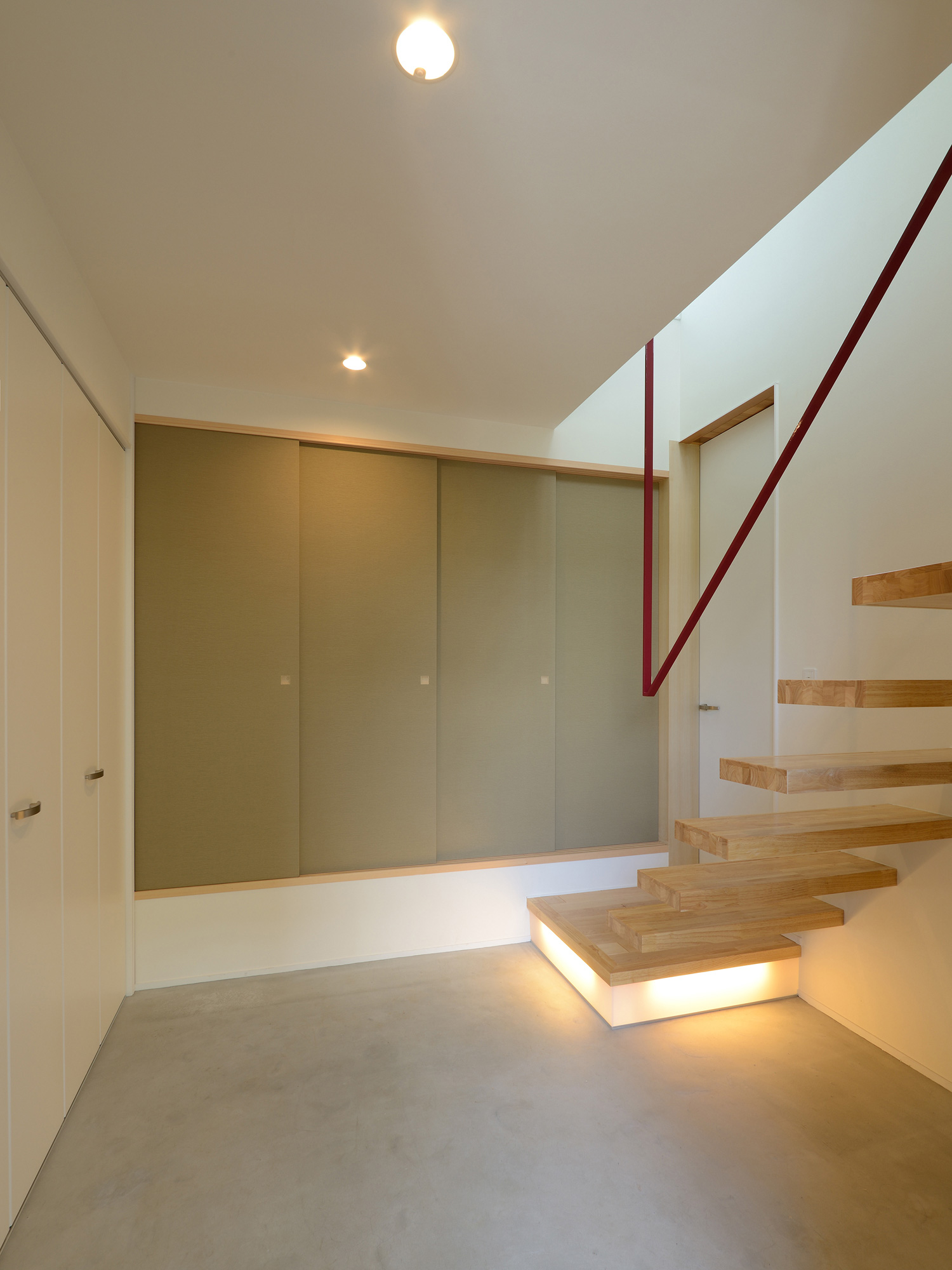 スケルトン階段の下に照明を取り付けたモルタルのおしゃれな玄関・デザイン住宅 注文住宅・デザイン住宅建築実例_『CASE561 TOHFU-HOUSE』_玄関