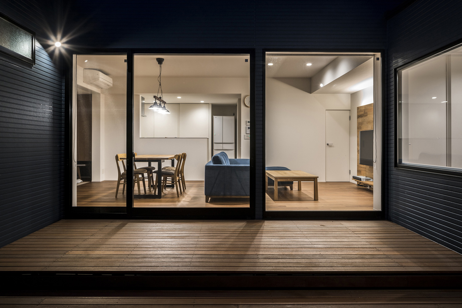 外壁に照明が取り付けられたウッドデッキのテラスからLDKを見た様子・デザイン住宅 注文住宅・デザイン住宅建築実例_『CASE563 pocket』_外観