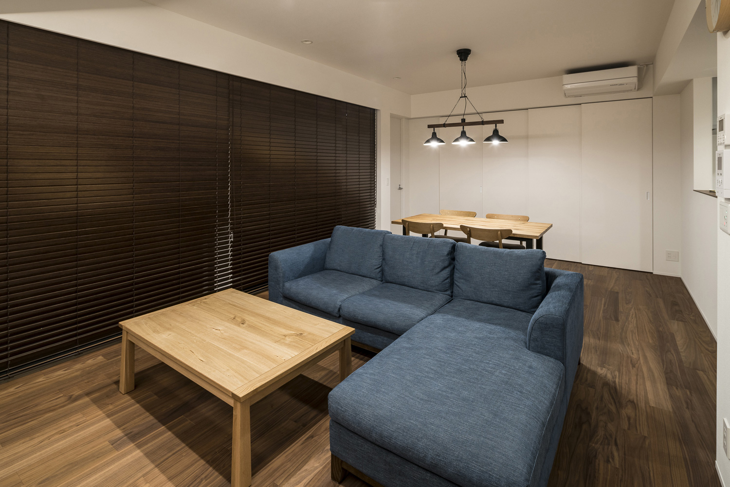 木のブラインドを取り付けた、木のサイドテーブルや青いL字ソファーを置いたLDK・デザイン住宅 注文住宅・デザイン住宅建築実例_『CASE563 pocket』_LDK