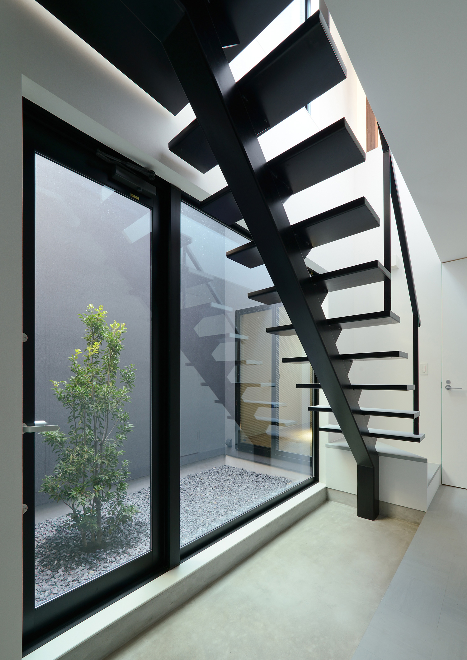 中庭に面した窓があるシンプルでおしゃれなモルタルの土間玄関・デザイン住宅 注文住宅・デザイン住宅建築実例_『CASE566 拡がりを内包する黒庭』_玄関