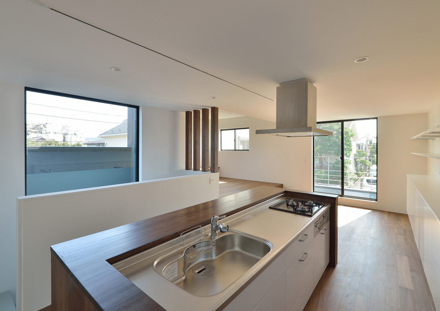 向かい側に窓がある、木のカウンター付きのアイランドキッチン・デザイン住宅 注文住宅・デザイン住宅建築実例_『CASE566 拡がりを内包する黒庭』_キッチン