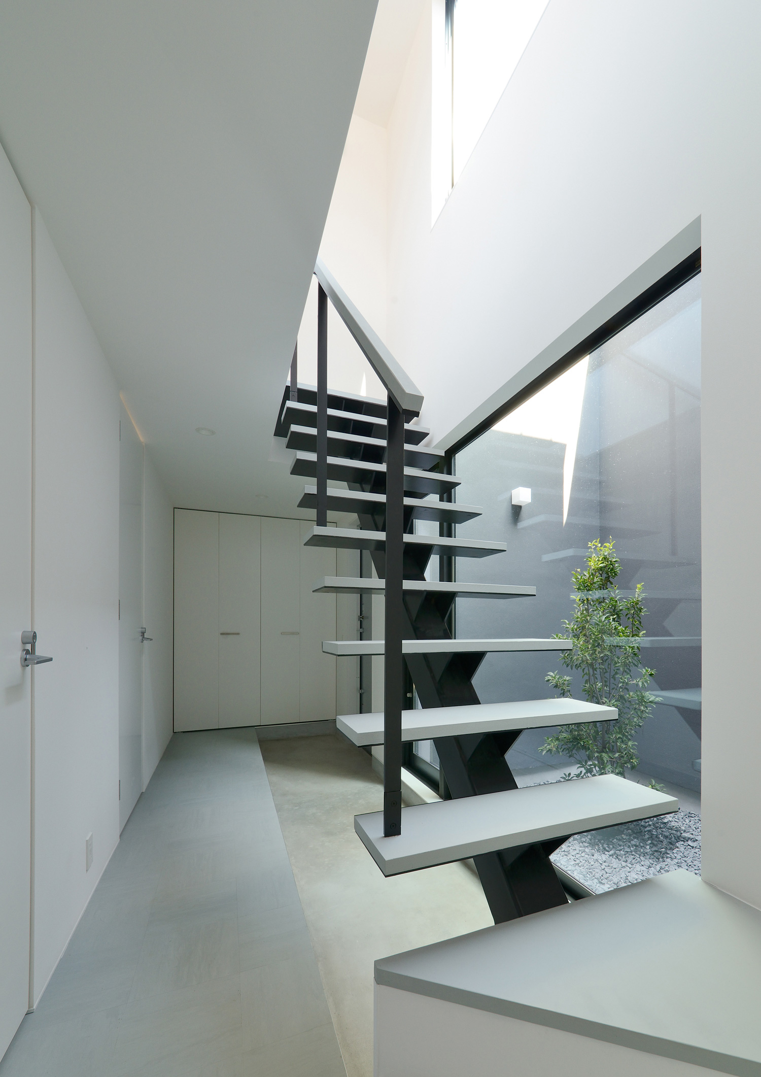 モルタルの玄関を横切るグレーと黒のスタイリッシュなスケルトン階段・デザイン住宅 注文住宅・デザイン住宅建築実例_『CASE566 拡がりを内包する黒庭』_階段