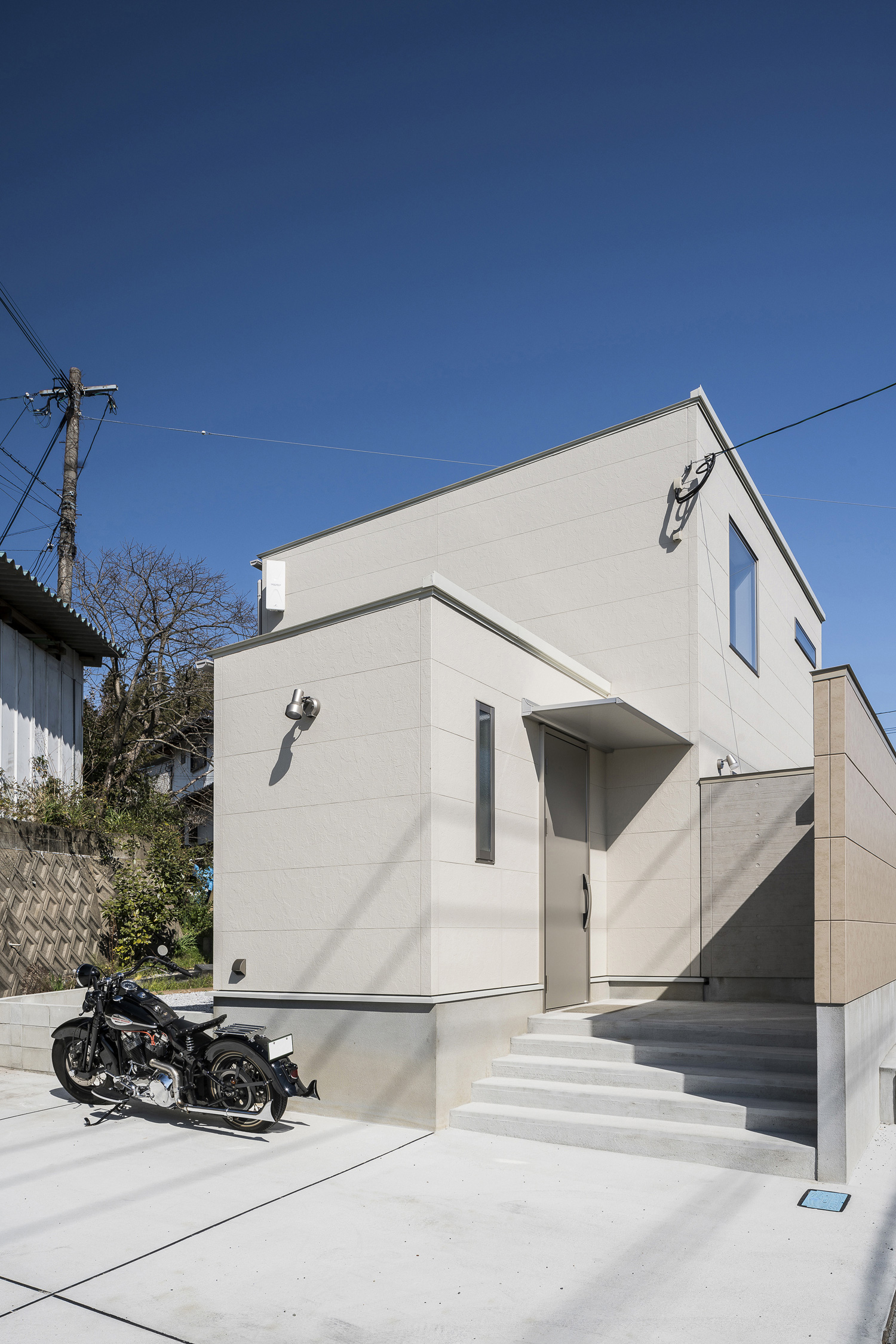 バイクが置かれた駐車スペースとコンクリートの階段アプローチがある白い外壁の家・デザイン住宅 注文住宅・デザイン住宅建築実例_『CASE567 lokki』_外観