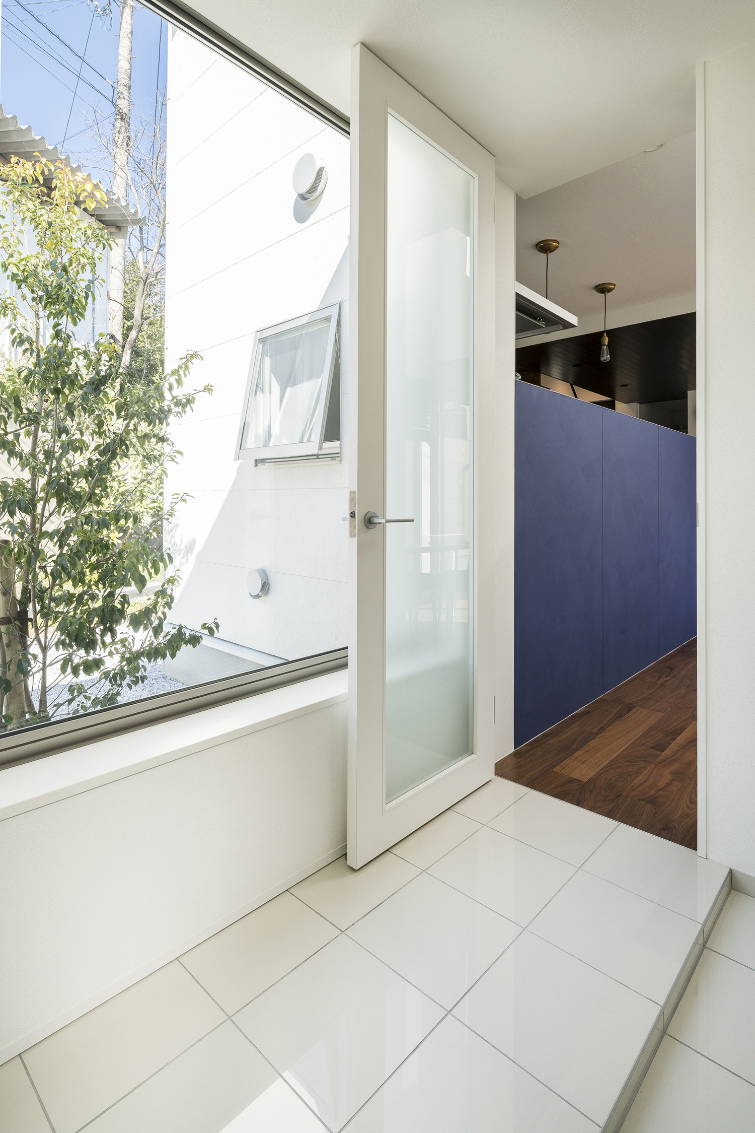 植栽の見える窓がある白いタイルの廊下・デザイン住宅 注文住宅・デザイン住宅建築実例_『CASE567 lokki』_玄関
