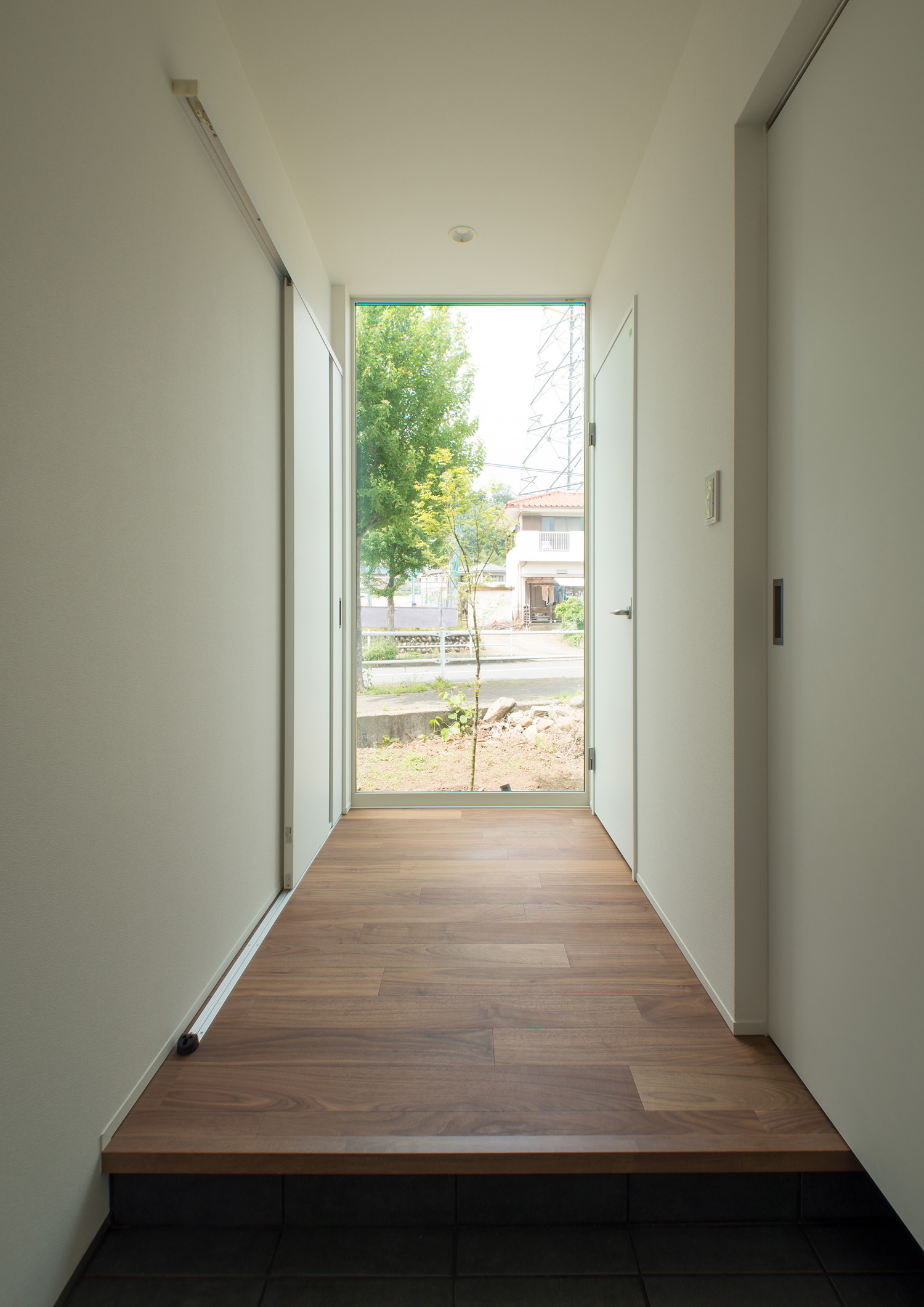 廊下の突き当りのガラス窓から植栽が見える玄関・デザイン住宅 注文住宅・デザイン住宅建築実例_『CASE575 緑を楽しむ家』_玄関