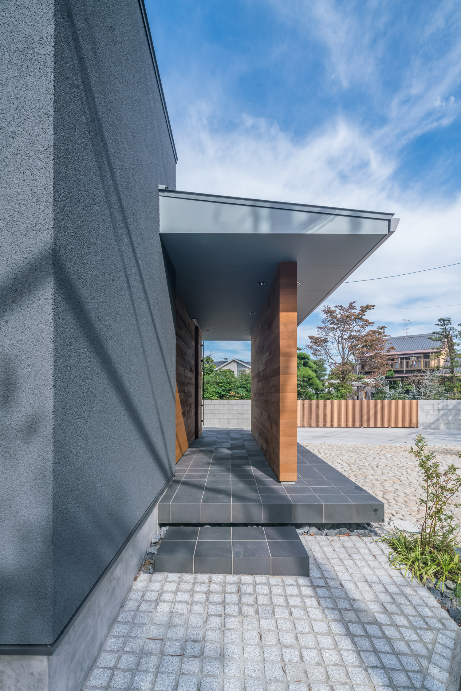 木の目隠し壁があり、黒いタイルの玄関アプローチ・デザイン住宅 注文住宅・デザイン住宅建築実例_『CASE576 回廊の家』_外観
