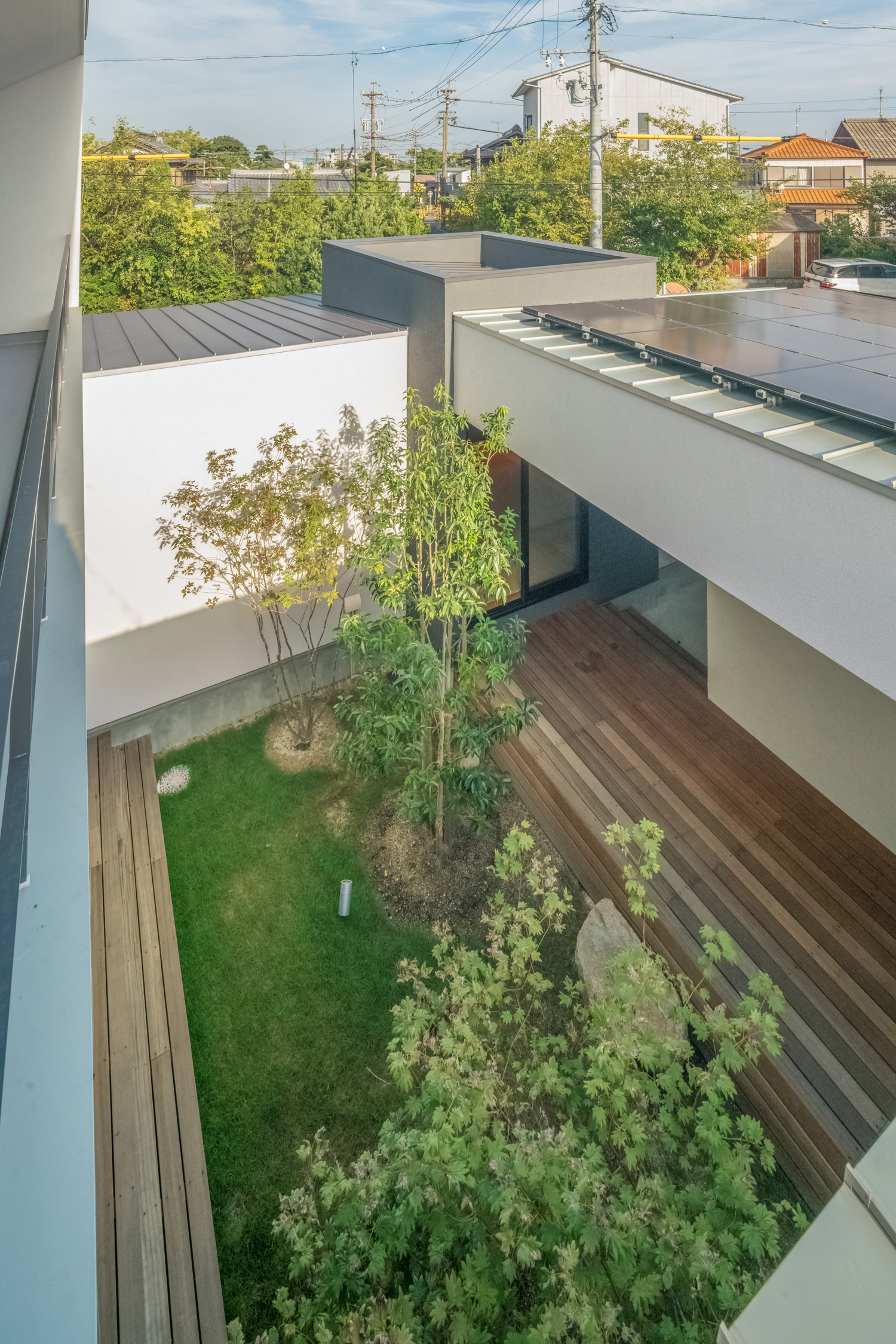 白い壁に囲まれた、芝生や植栽のある中庭を上から見た様子・デザイン住宅 注文住宅・デザイン住宅建築実例_『CASE576 回廊の家』_中庭