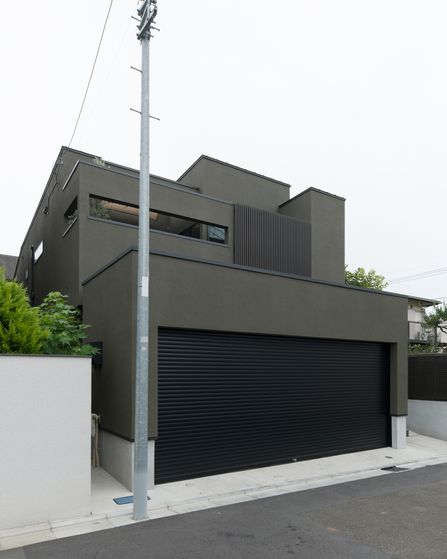 黒いシャッター付きのガレージや目隠し壁付きのベランダがあるカーキの外壁の家・デザイン住宅 注文住宅・デザイン住宅建築実例_『CASE577 紬(つむぎ)の家』_外観