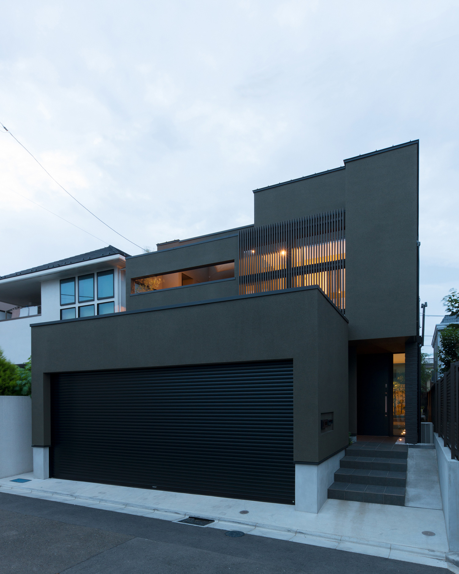 ベランダにあるルーバーの目隠しや玄関扉の横の窓から光が漏れる外観・デザイン住宅 注文住宅・デザイン住宅建築実例_『CASE577 紬(つむぎ)の家』_外観