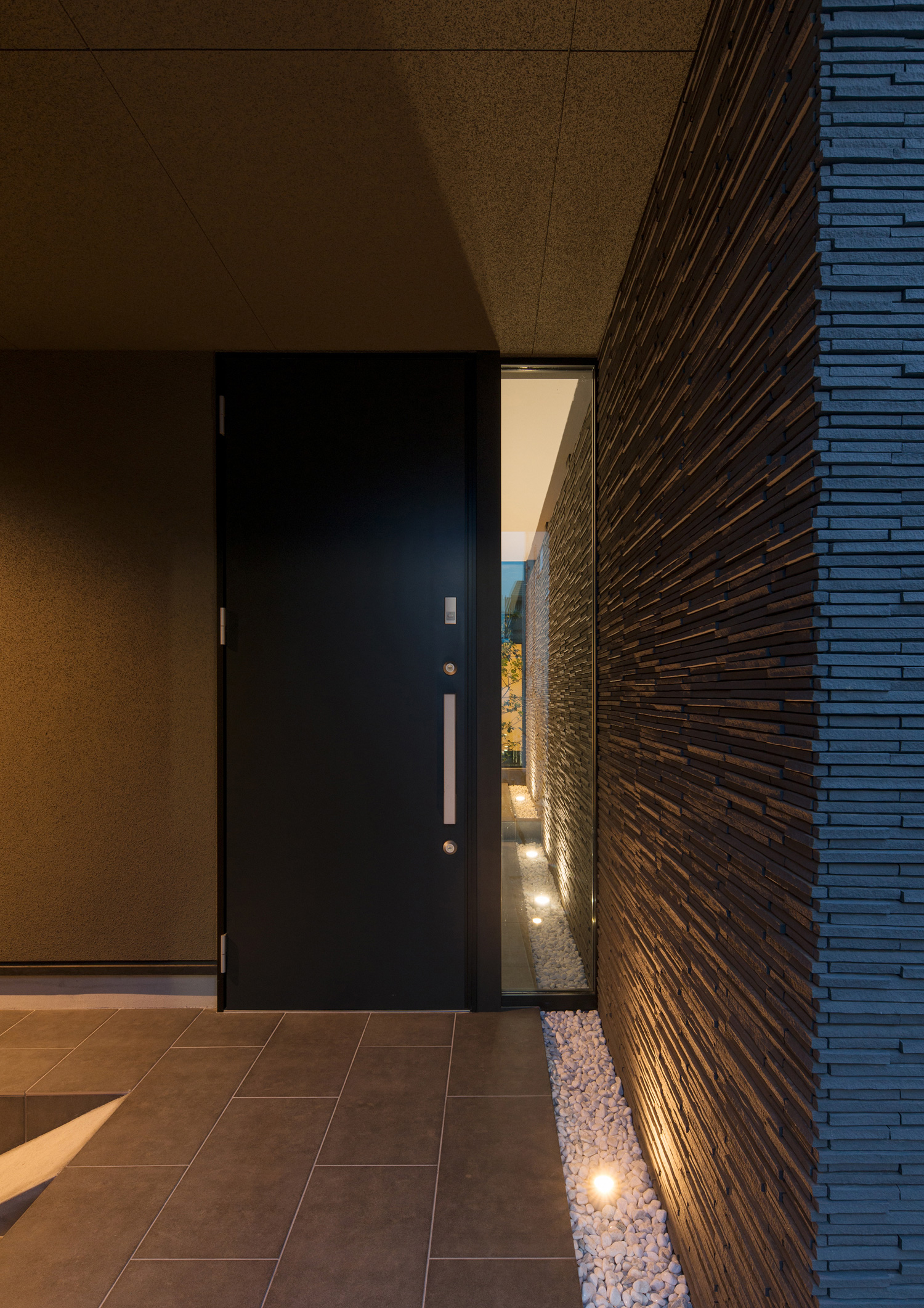 黒い玄関扉の横に縦長のスリット窓があるタイルの玄関・デザイン住宅 注文住宅・デザイン住宅建築実例_『CASE577 紬(つむぎ)の家』_外観