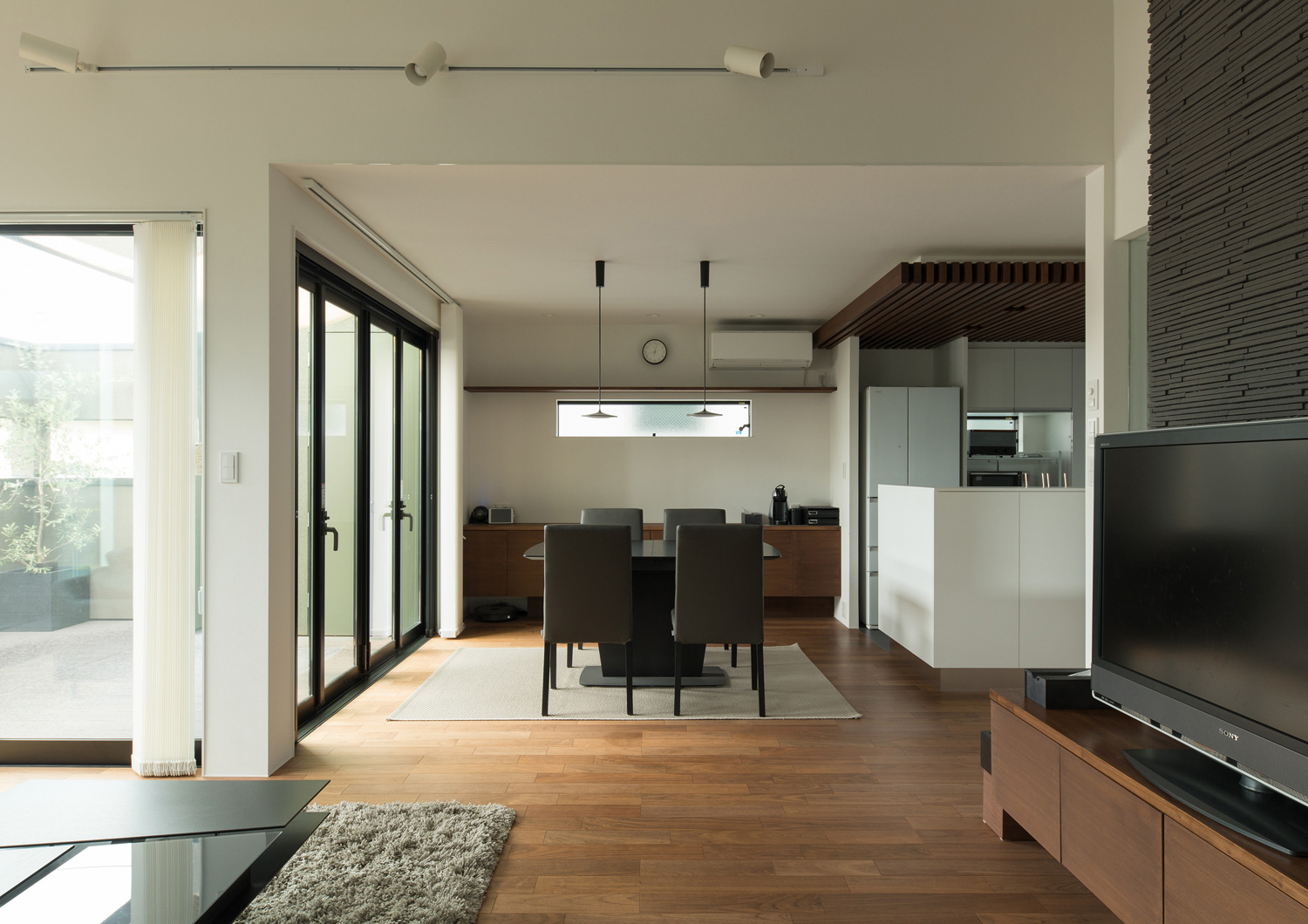 黒いダイニングテーブル部分にカーペットが敷かれたフローリングのLDK・デザイン住宅 注文住宅・デザイン住宅建築実例_『CASE577 紬(つむぎ)の家』_LDK